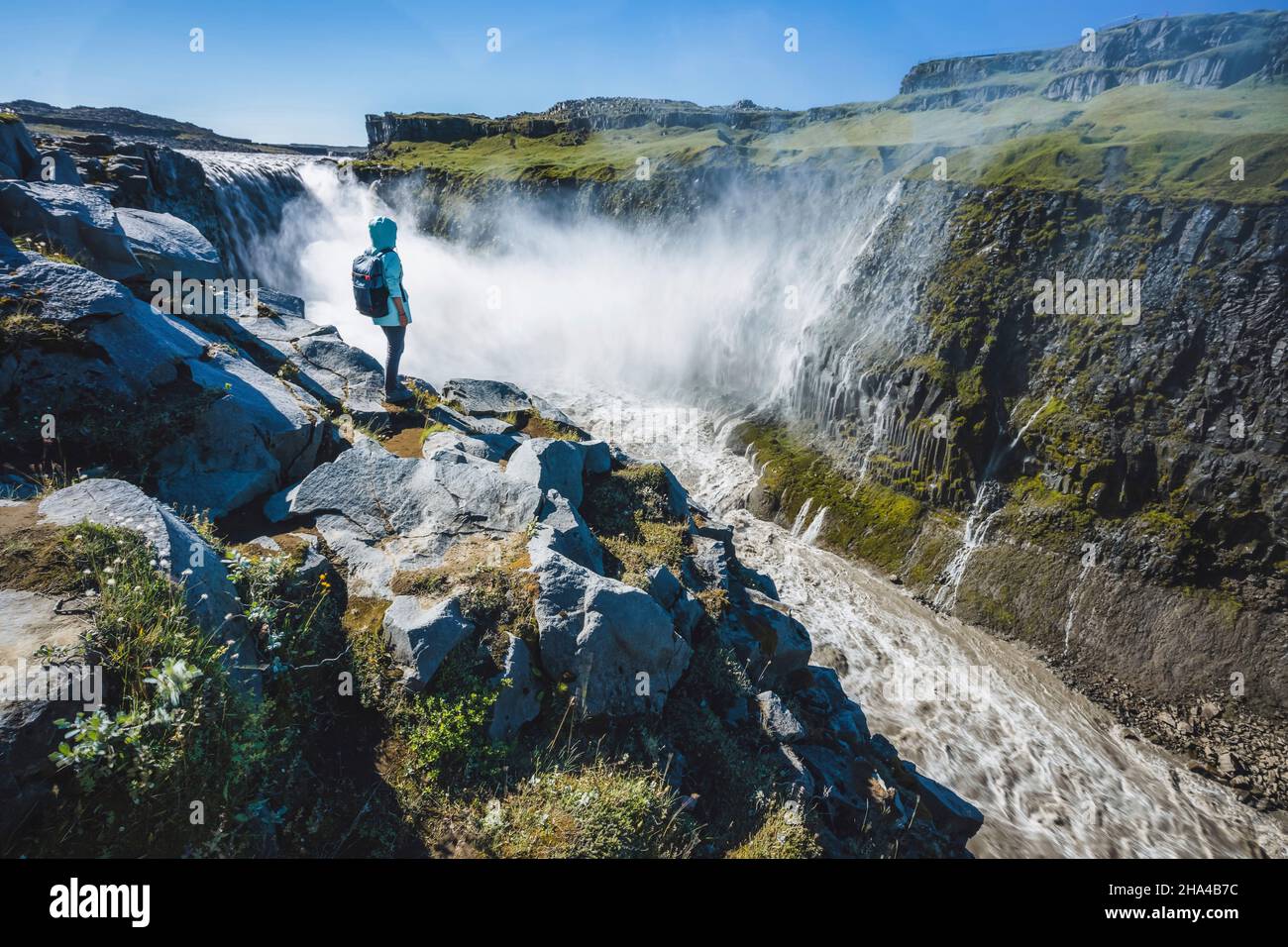 Frau auf der Klippe dettifoss Wasserfall im Nordosten islands. dettifoss ist ein Wasserfall im vatnajokull Nationalpark, der als der mächtigste Wasserfall in europa gilt. Stockfoto