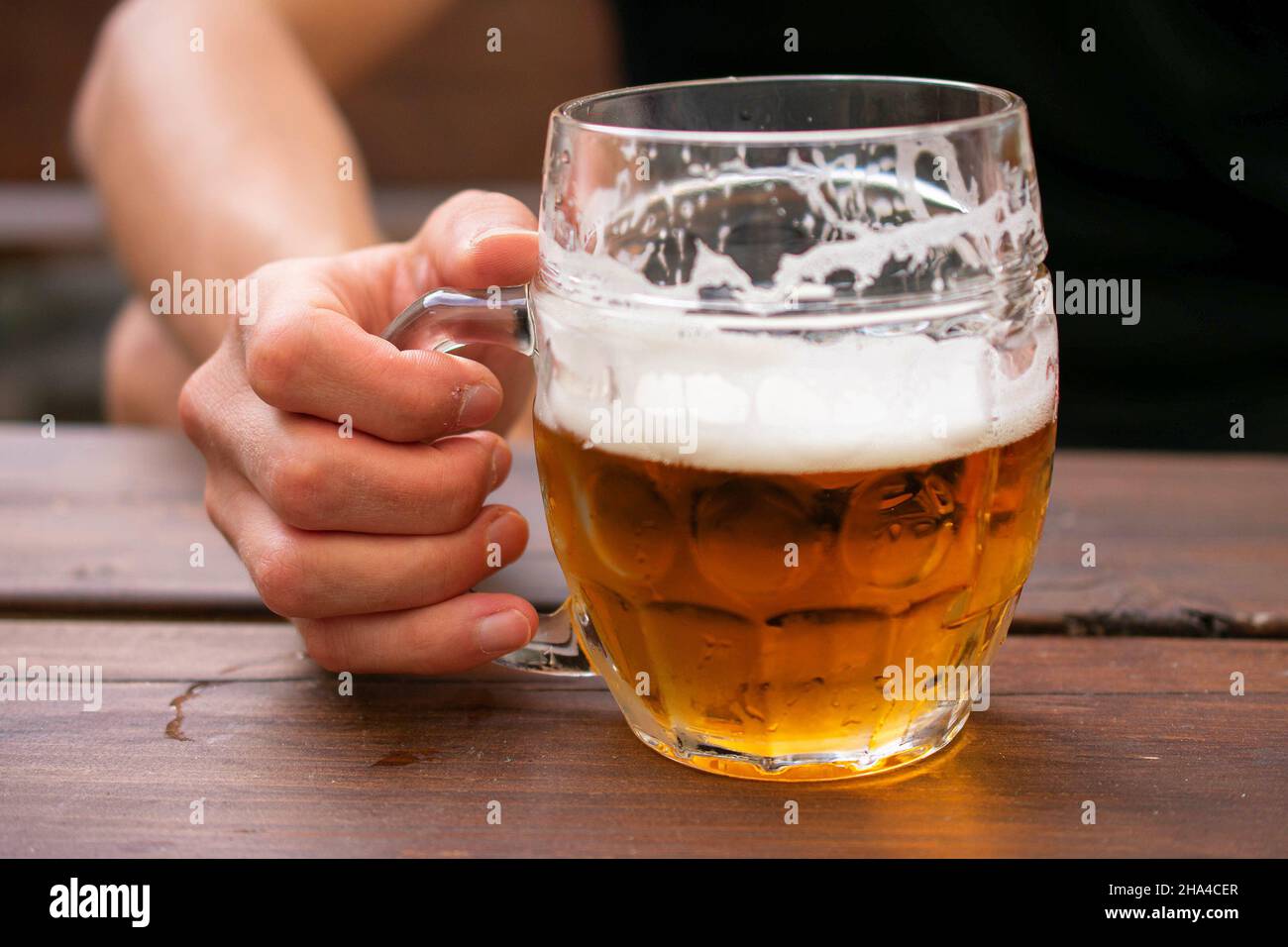 Weißer Mann, der halb betrunkenes Pint Bier in der Hand in Nahaufnahme hält Stockfoto