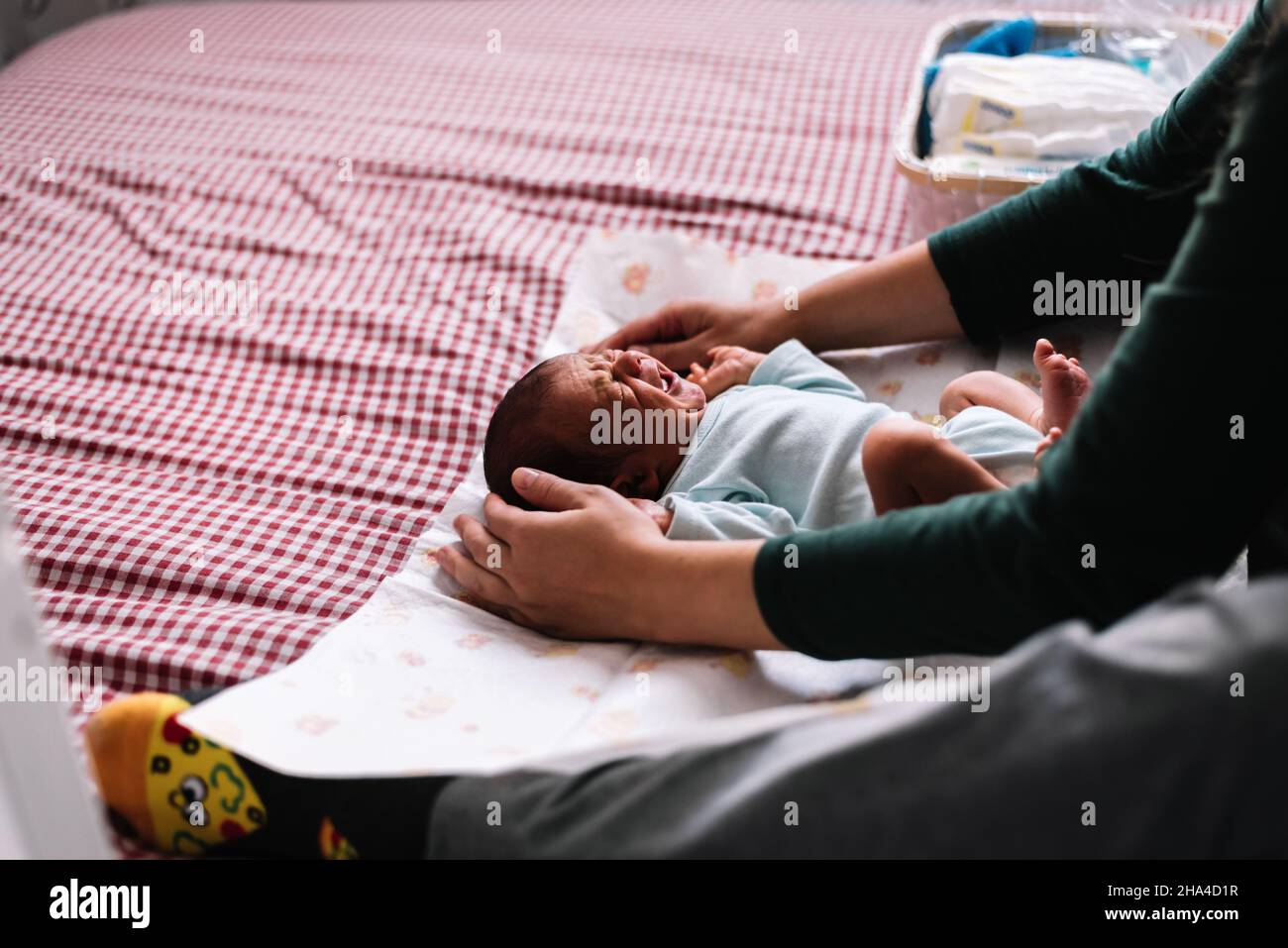 Mutter wechselt ihr neugeborenes Baby im Bett. Stockfoto