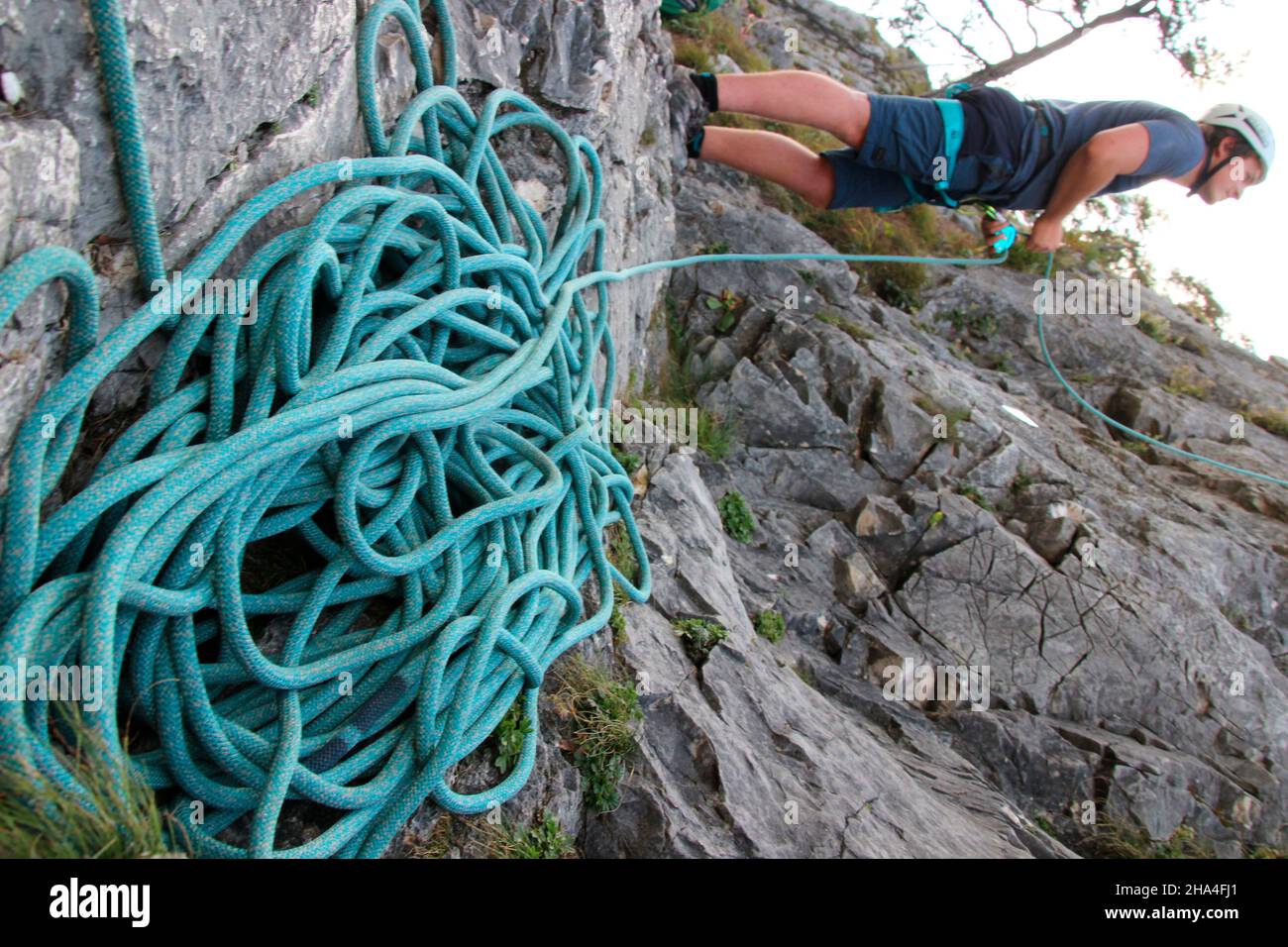 Der junge Mann sichert sich seinen Kollegen beim Klettern im Klettergarten 'Sonnenplatten scharnitz' karwendelgebirge,scharnitz,tirol,österreich Stockfoto