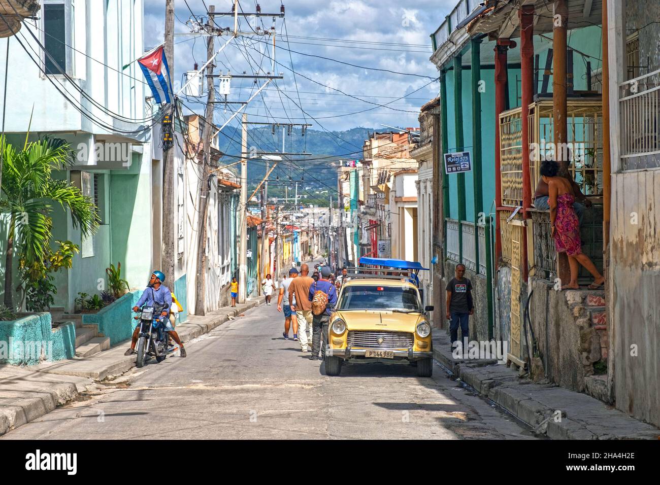 Straßenszene mit bunten Häusern und altem amerikanischen Auto in Santiago de Cuba, der Hauptstadt der Provinz Santiago de Cuba auf der Insel Kuba, Karibik Stockfoto