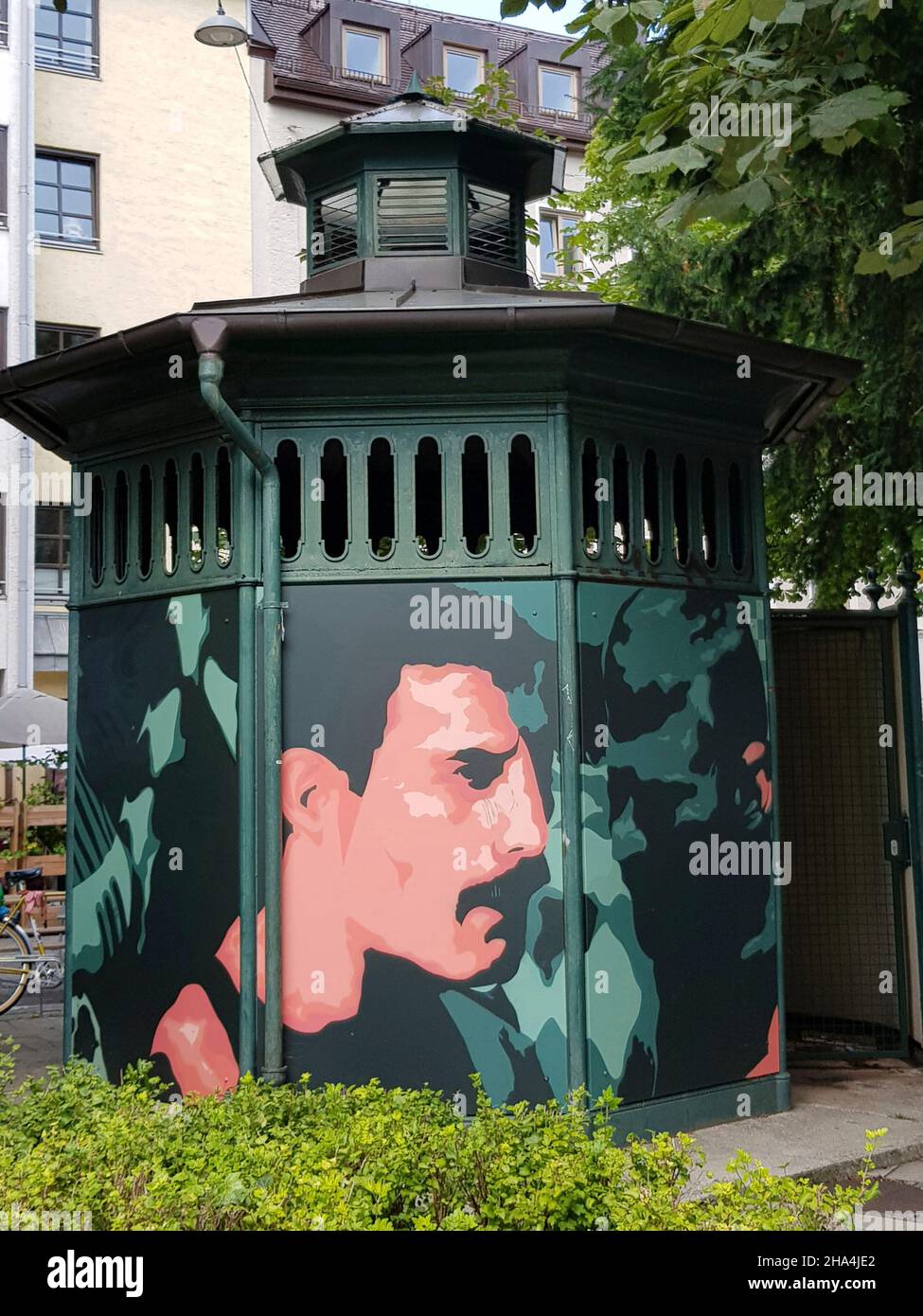 'The Pissoir', gusseisernes Achteck aus dem Jahr 1900, münchner holzplatz, Street Art Projekt des Künstlers martin arz. Seit 2020 schmücken drei Persönlichkeiten die Fassade des denkmalgeschützten Urinals: albert einstein, freddie Mercury, rainer-werner fassbinder, alle drei lebten vorübergehend in münchen. Stockfoto