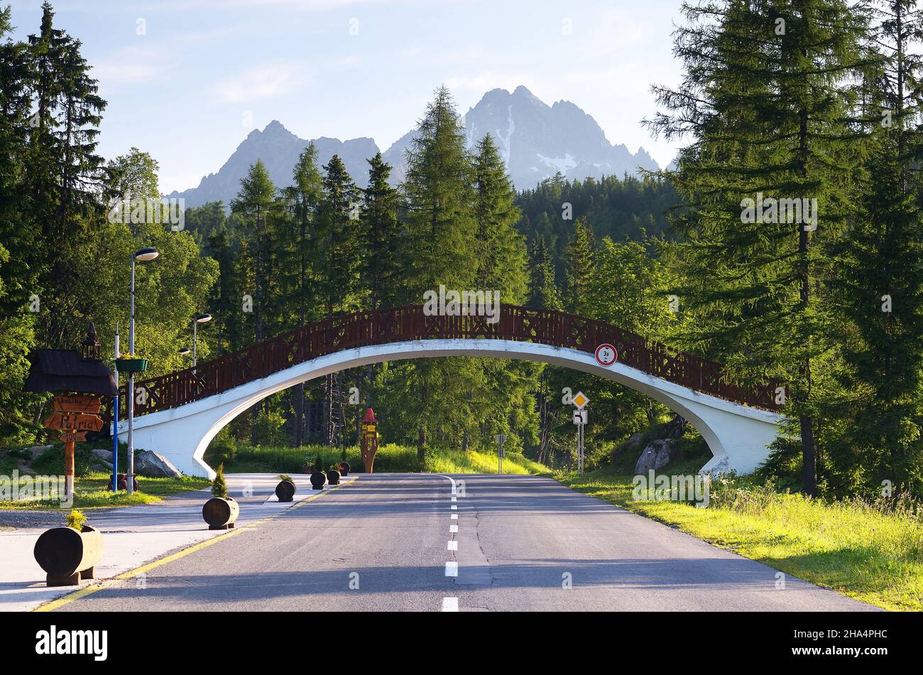 SLOWAKEI, SHTRBSVE PLESO - JUNI 29: Sommerlandschaft mit Straße in einem Bergort und einer Fußgängerbrücke. Tatra, Slowakei Stockfoto