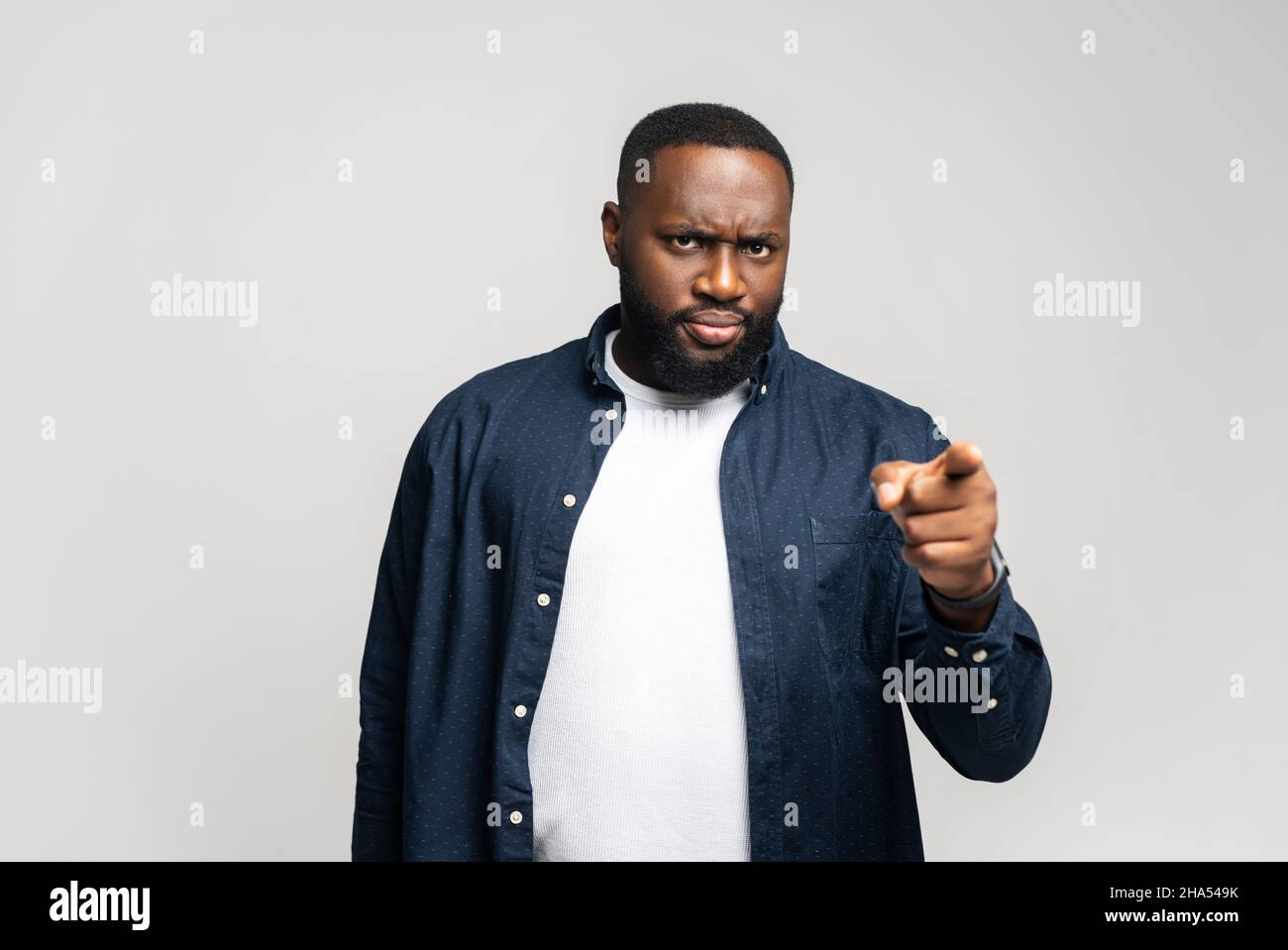 Ernster afroamerikanischer Kerl, der mit dem Zeigefinger auf die auf grauem Hintergrund isolierte Kamera zeigt und dich wählt Stockfoto