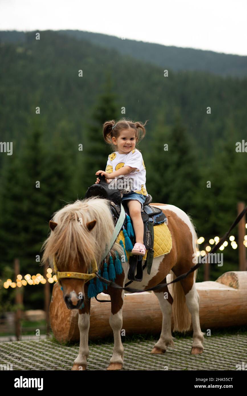 Pretty Emotion Baby Mädchen reiten ein Pony und lächelnd. Stockfoto