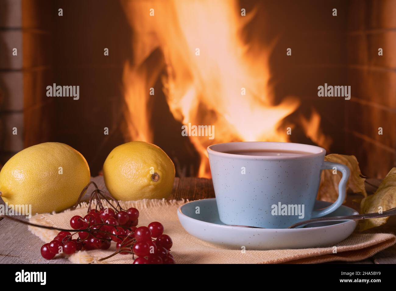 Gemütliche Szene vor dem Kamin Tasse Tee, Beeren und Zitronen. Stockfoto