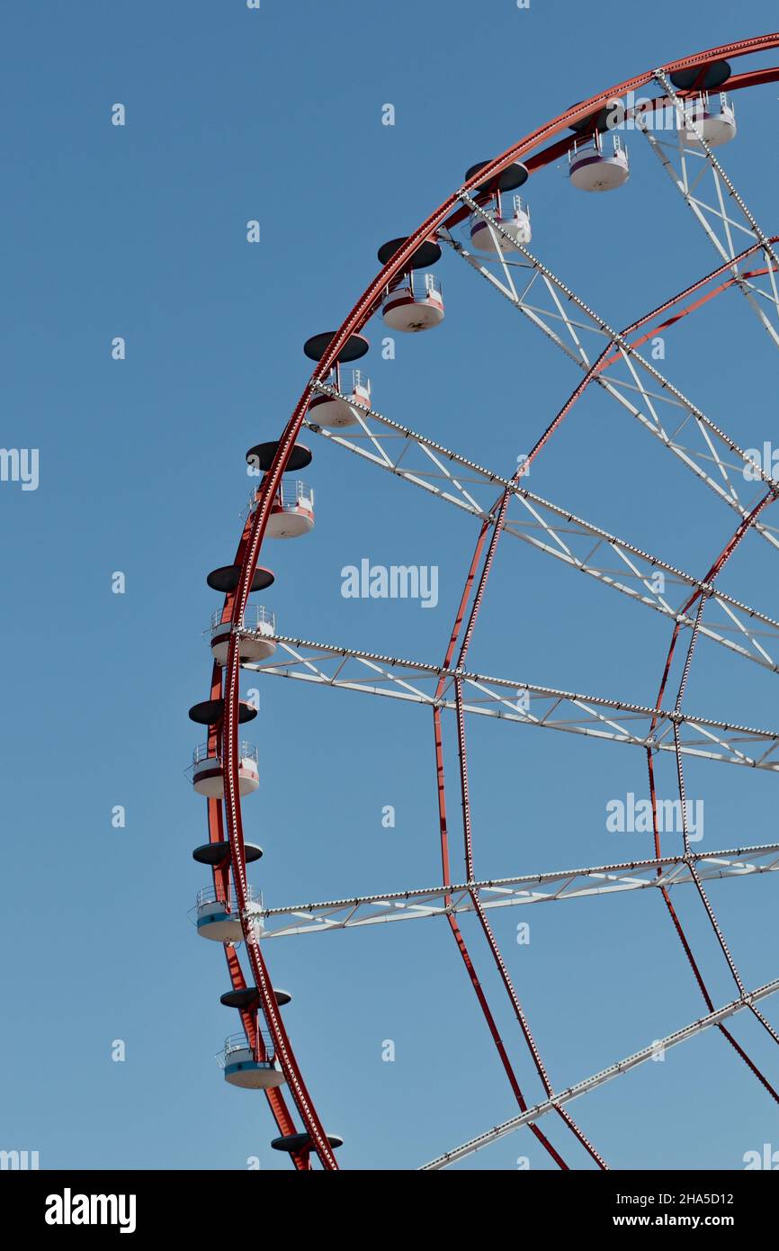 Riesenrad im Vergnügungspark gegen die Sonne fotografiert. Bau der Attraktion mit rosa Himmel und Wolken im Hintergrund. Abenteuer Stockfoto