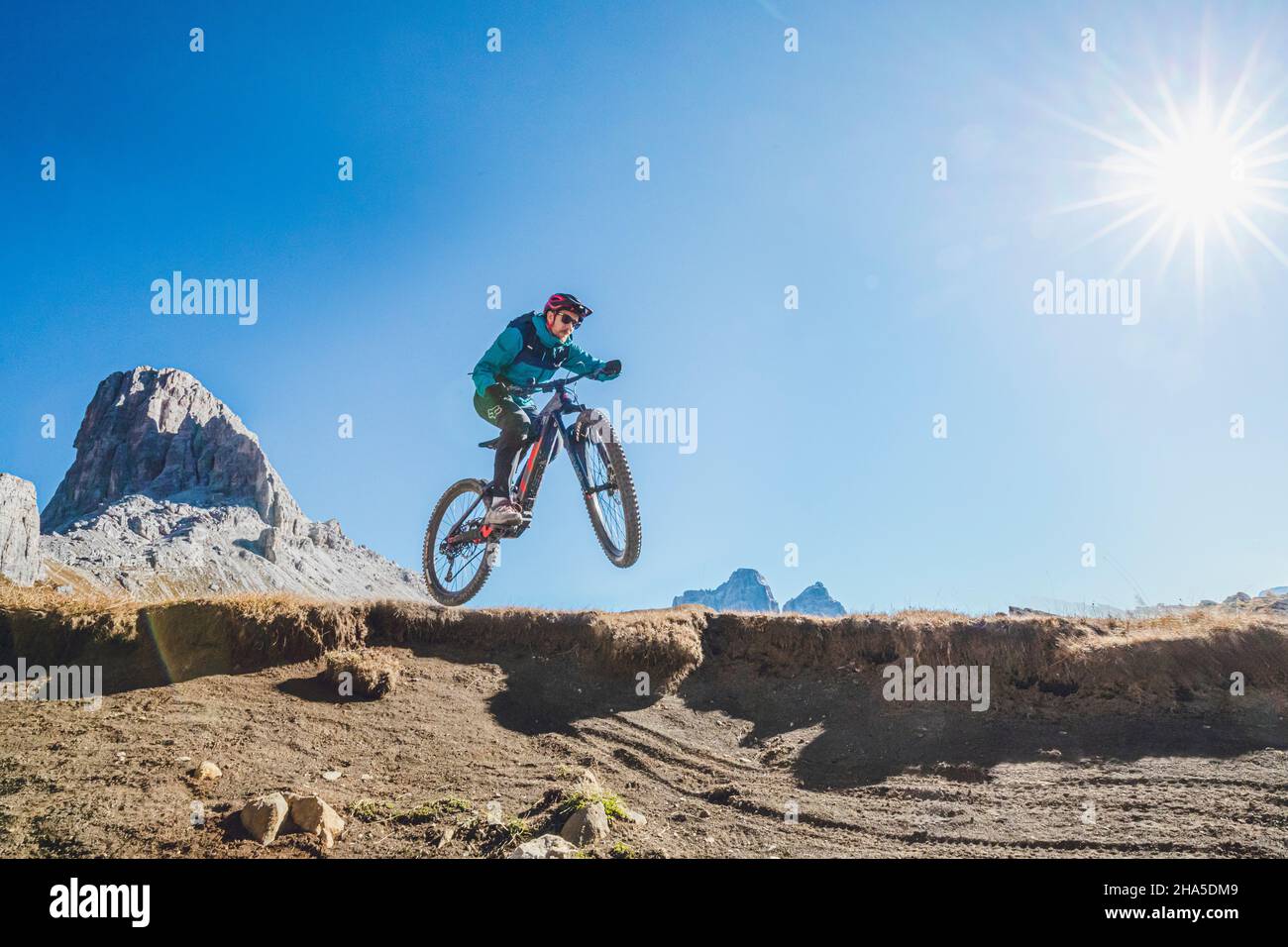 E-Biker in Aktion springt mit seinem Fahrrad, Herbstlandschaft, dolomiten, san vito di cadore, belluno, veneto, italien Stockfoto