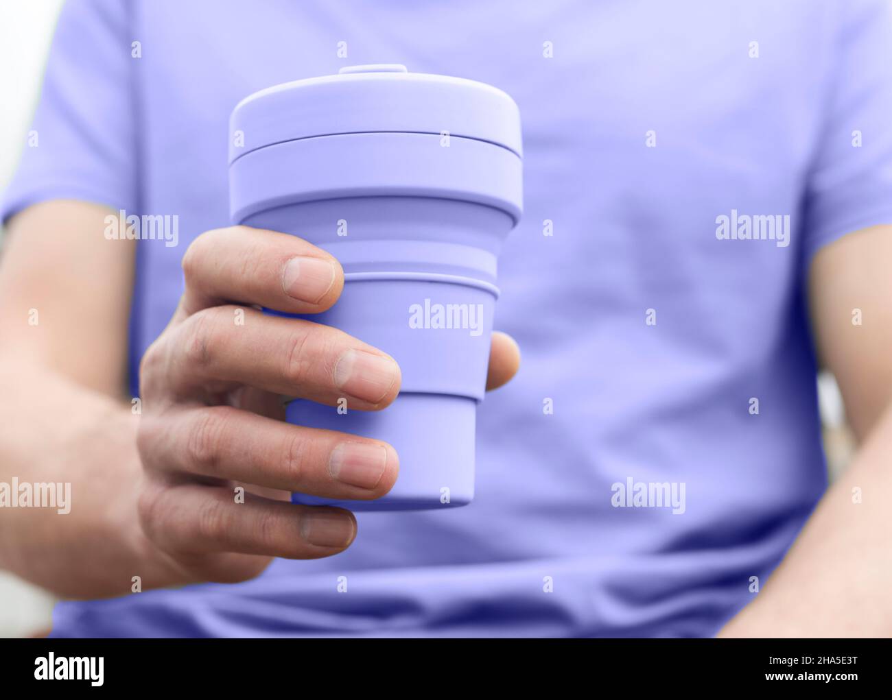 Sehr peri zusammenklappbare Tasse in der Hand der Person in veri pery farbige Kleidung. Stockfoto