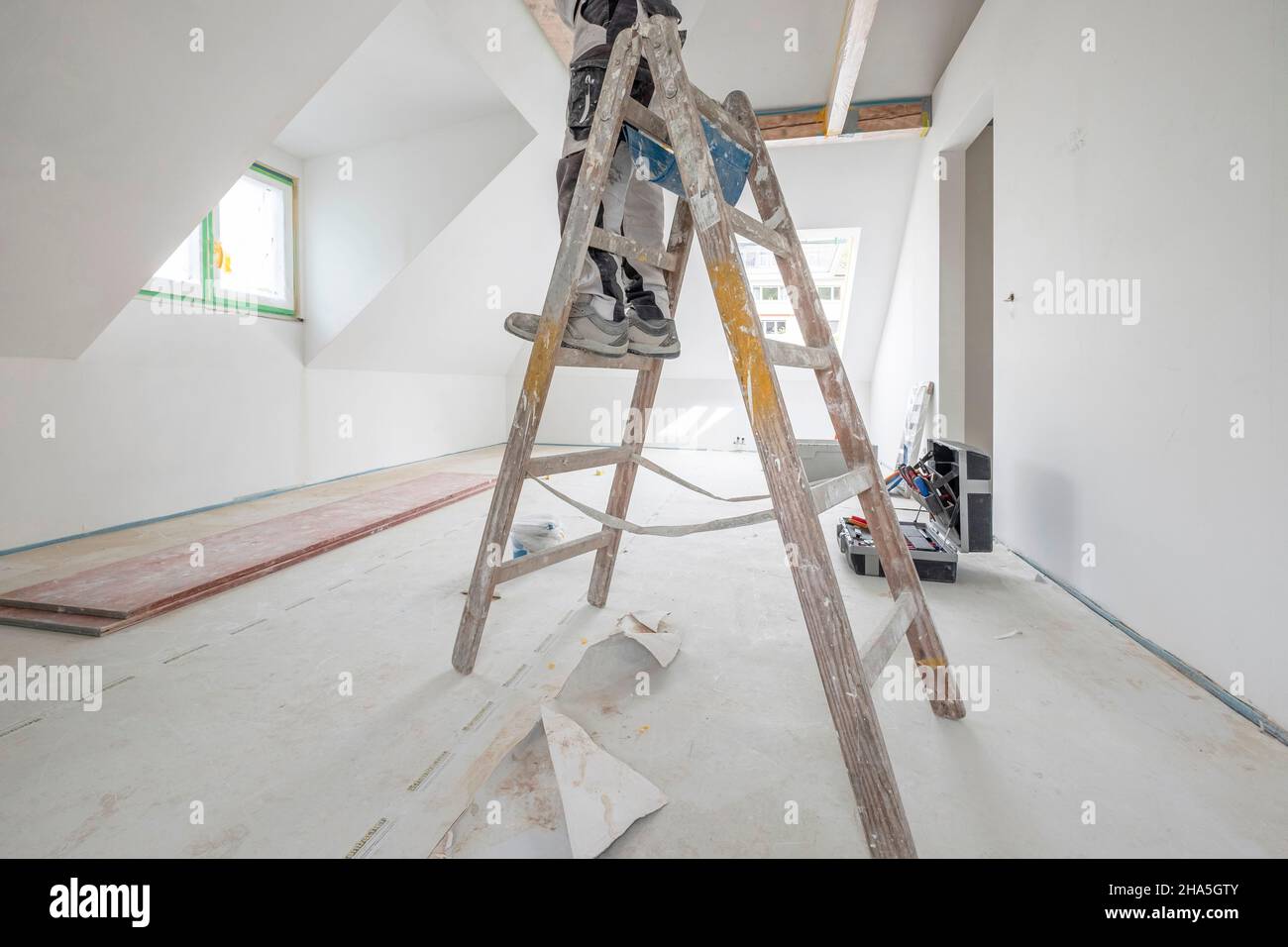 Baustelle, Sanierung und Renovierung einer Wohnung, Maler auf einer Leiter im Dachgeschoss Stockfoto