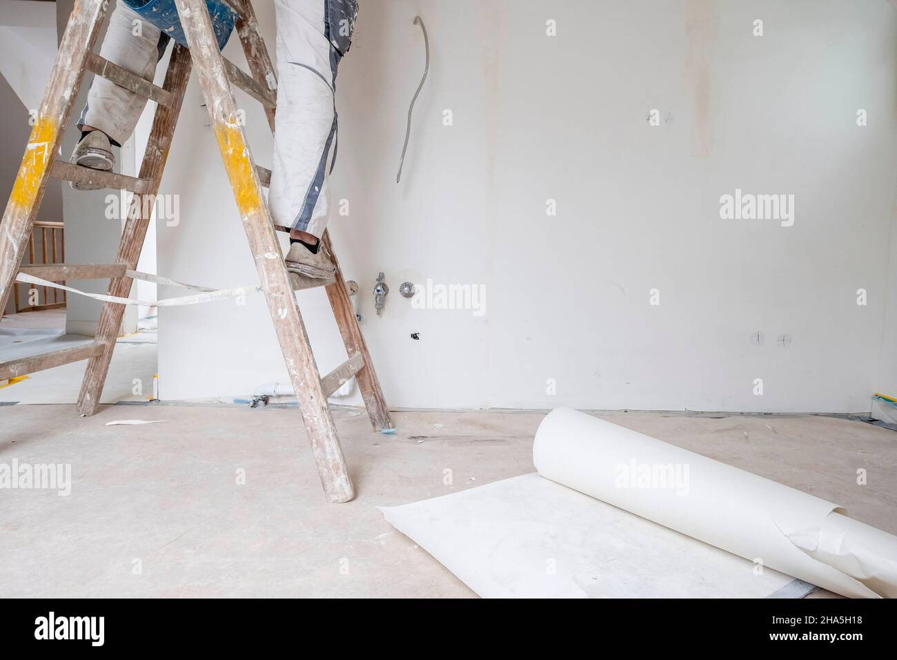 Baustelle, Sanierung und Renovierung einer Wohnung, Maler steht auf einer Leiter in einem leeren Raum Stockfoto