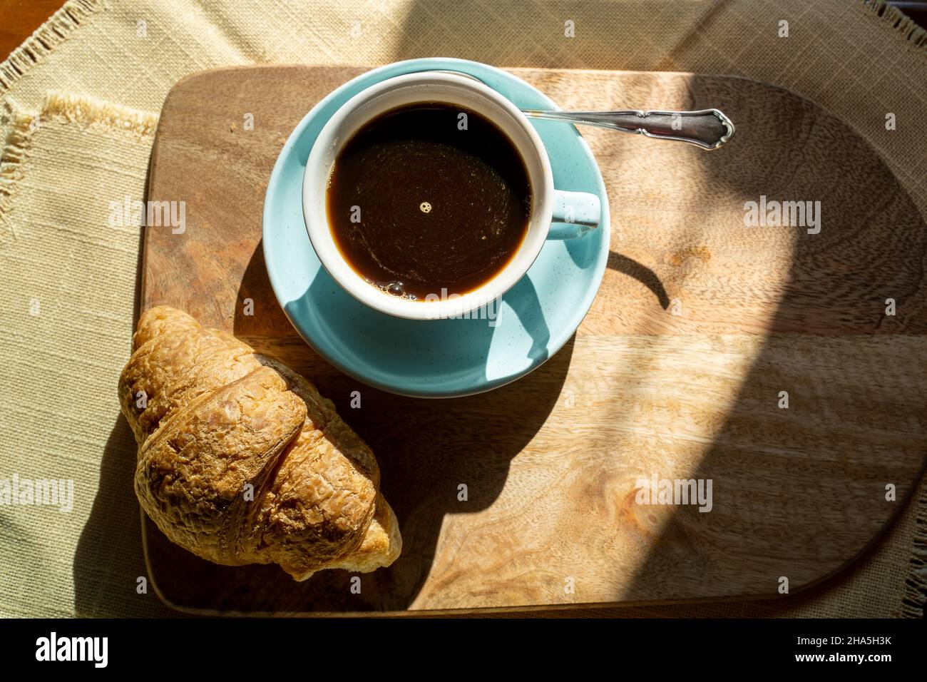 Tasse Kaffee, Croissant, beleuchtet vom Sonnenlicht, Herbsttag. Stockfoto