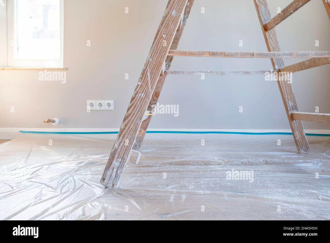 Baustelle, Sanierung und Renovierung einer Wohnung, Malerleiter auf einem mit Folie bedeckten Boden Stockfoto