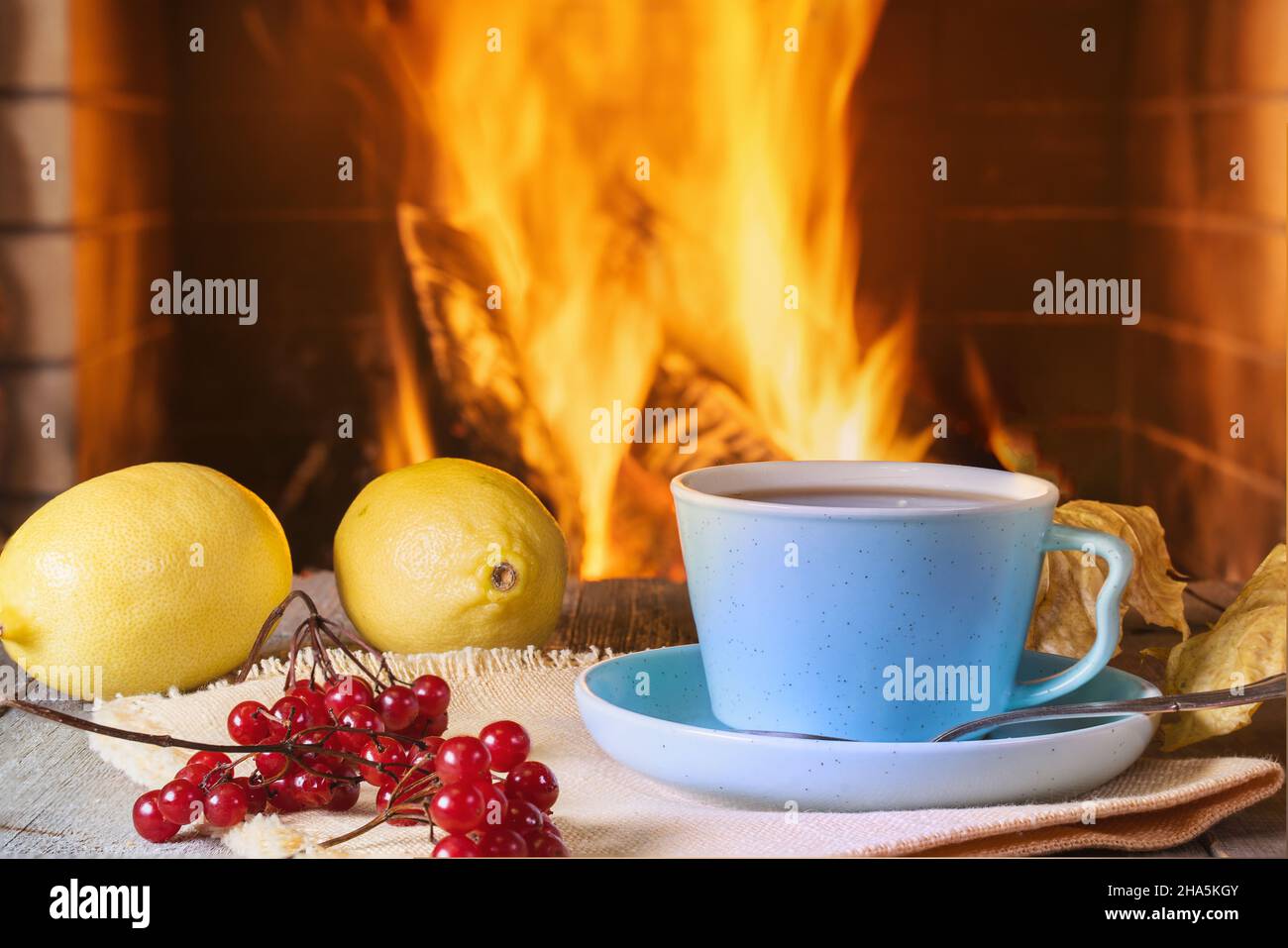 Gemütliche Szene vor dem Kamin Tasse Tee, Beeren und Zitronen. Stockfoto