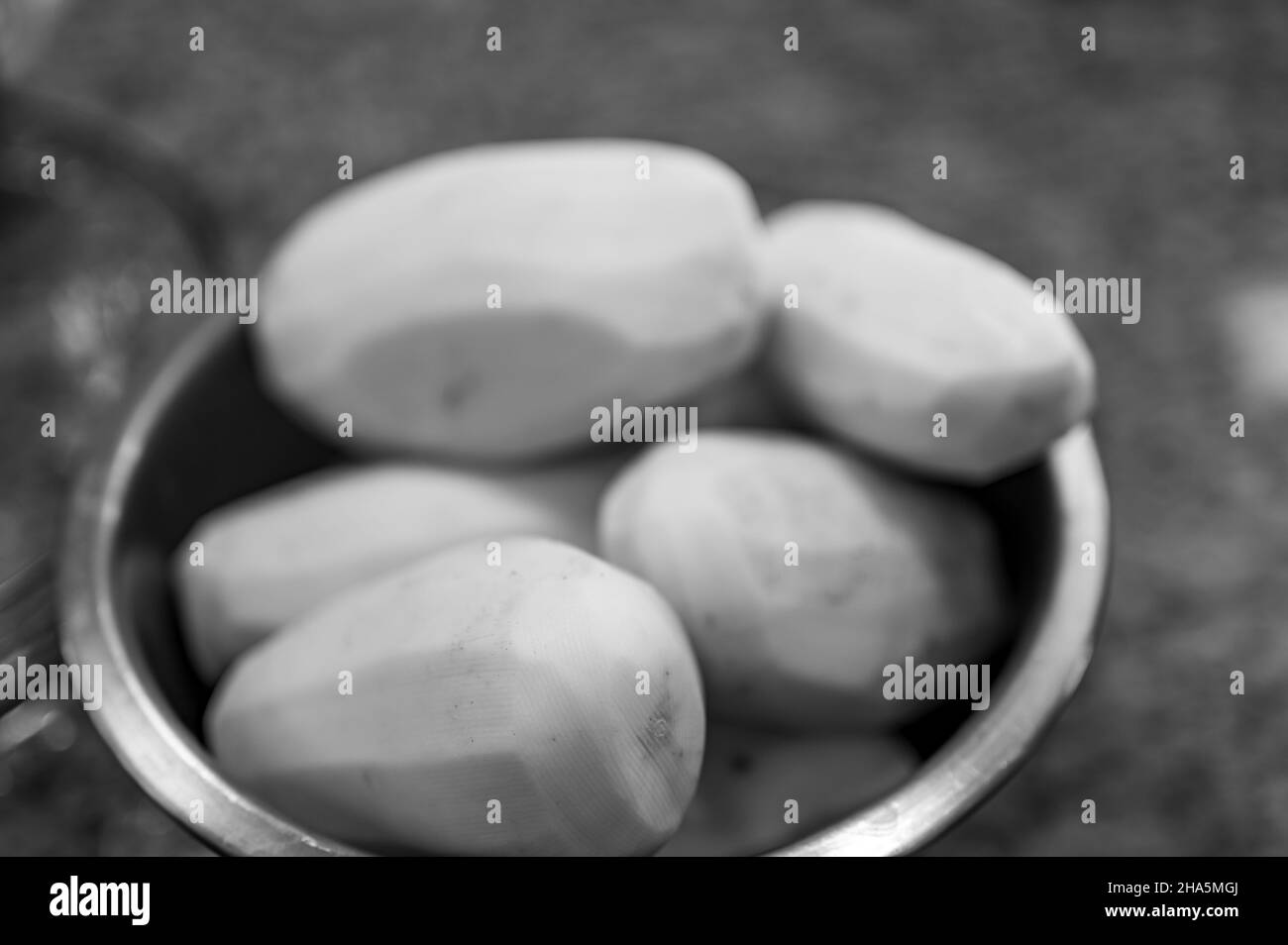 Konzentrieren Sie sich selektiv auf geschälte Kartoffeln in einer Metallschüssel, die in Scheiben geschnitten und gekocht werden kann Stockfoto