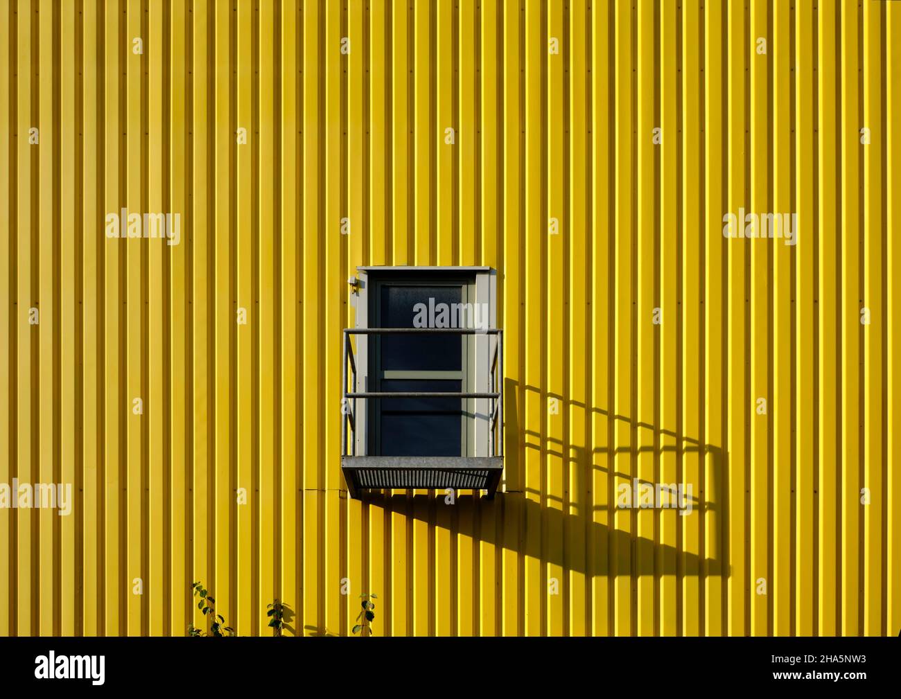 Bunte Industriearchitektur, gelbe Fassade, Tür mit Schatten, Stockfoto