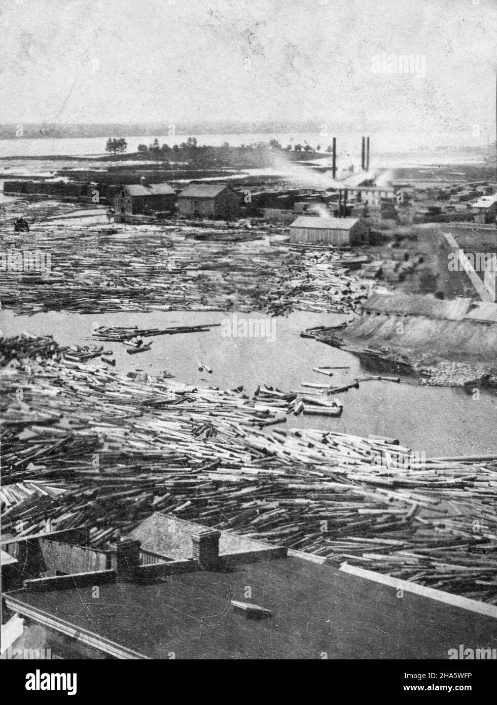 Moira River in Belleville, Ontario, aufgenommen von William Spence Clarke, wahrscheinlich vom Turm des Rathauses, um 1920. In der Ferne ist Zwick's Island zu sehen, mit Holtons Holzmühlen in der Water Street in der Mitte des Bildes und vielen Holzstämmen im Fluss im Vordergrund. Stockfoto