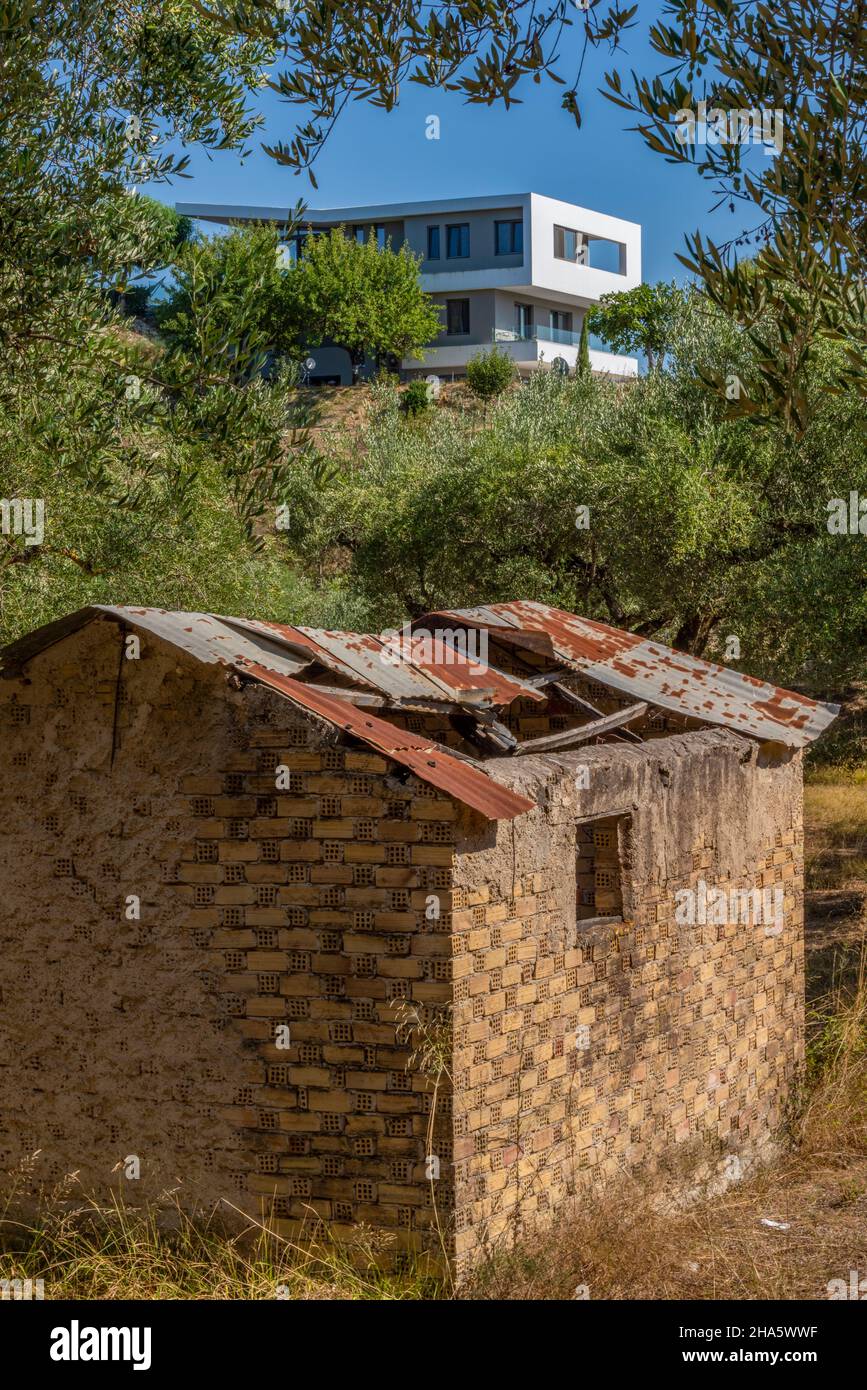 Hochmoderne Architektur-Villa in Hügeln auf der griechischen Insel zakynthos oder Zante mit einer alten griechischen Olivenbauernhütte oder einem Gebäude im Vordergrund. Stockfoto