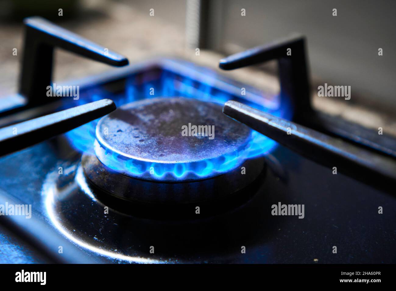 Herd als Heizung. Verschwendung natürlicher Ressourcen. Die blaue Flamme des Gaskochfelds erzeugt Treibhausgasemissionen. Küchenherd rosten auf einem Brenner, der mit Brennstoff betrieben wird Stockfoto