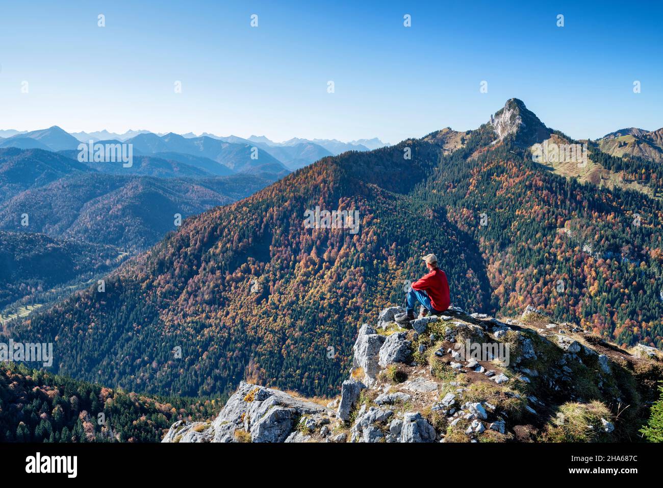 Wanderer auf dem leonhardstein genießen an einem sonnigen Herbsttag den Blick über die bayerischen voralpen. Berge, Hügel und Wälder unter blauem Himmel. mangfallberge, bayern, deutschland, europa Stockfoto