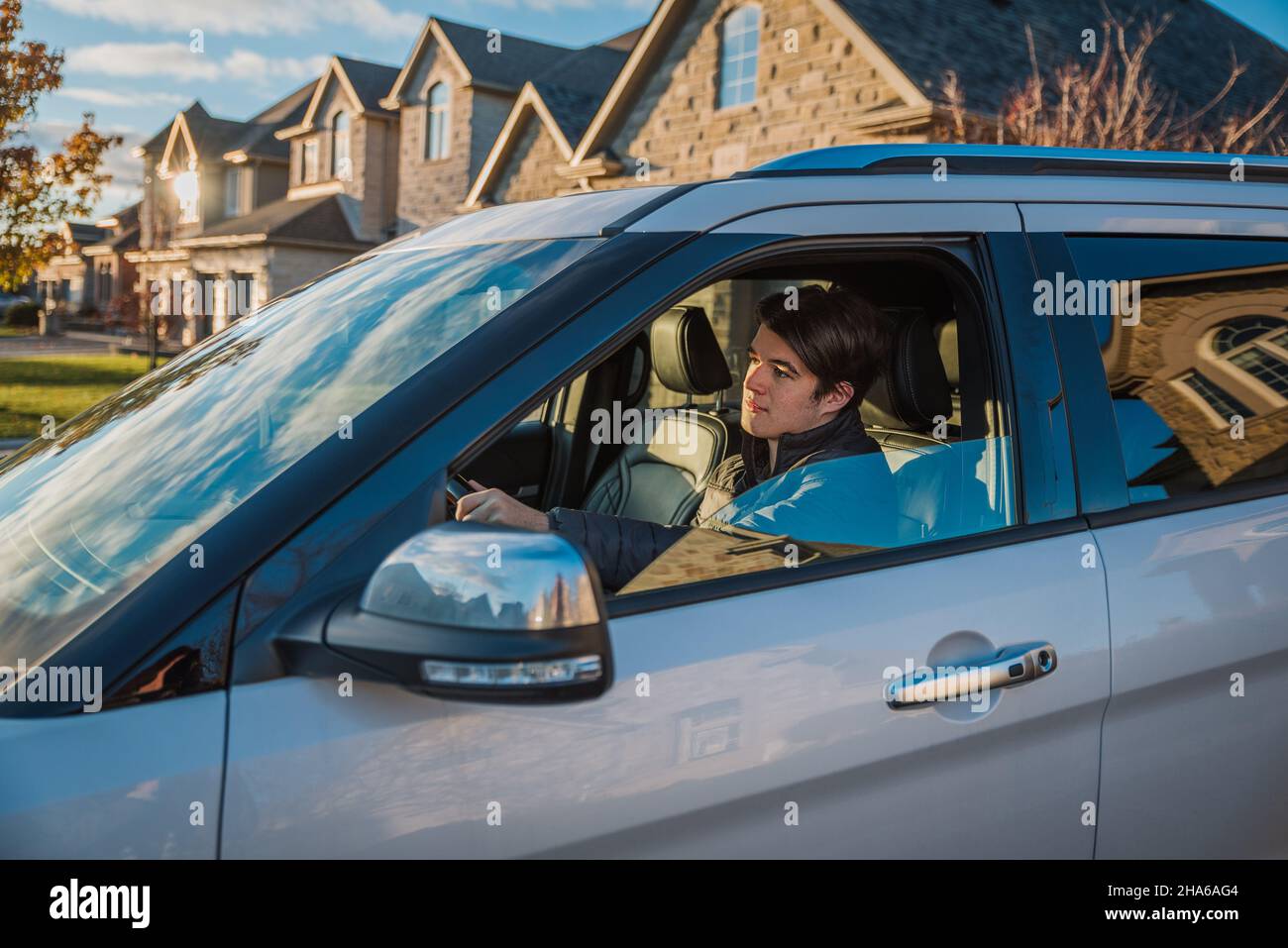 Teenager, der auf dem Fahrersitz des Fahrzeugs sitzt und das Fahren lernt. Stockfoto