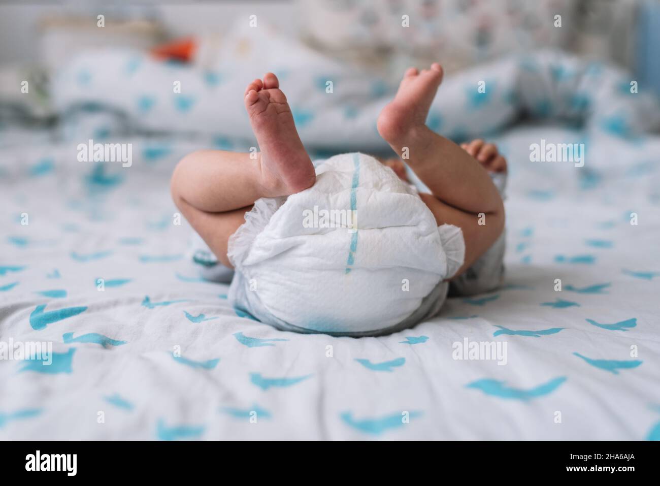 Blick auf ein Baby, das im Bett liegt. Füße hoch und Windel. Stockfoto