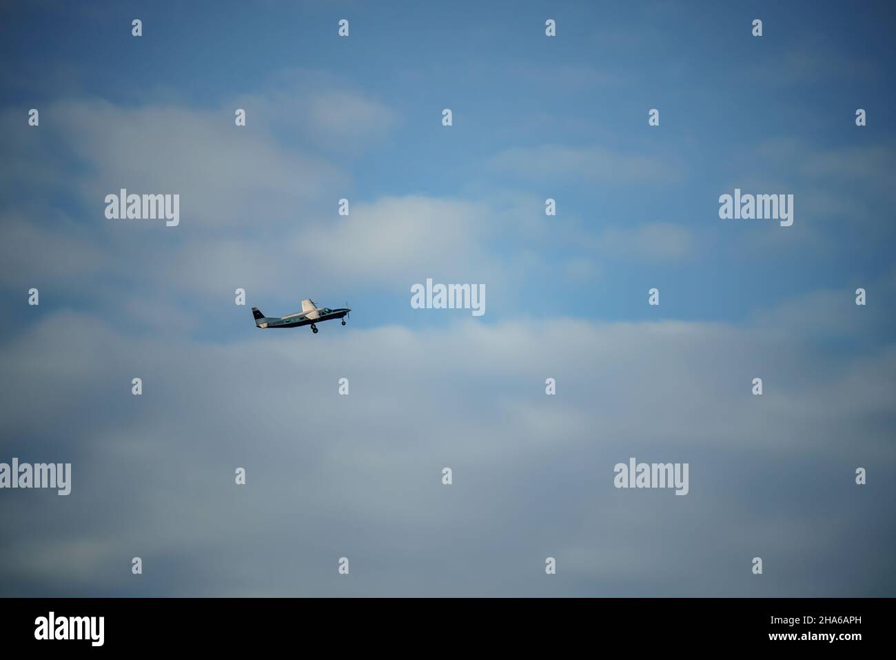 Ein Cessna Grand Caravan 208B G-CPSS Flugzeug, das in einem blau-weißen Wolkenhimmel klettert Stockfoto