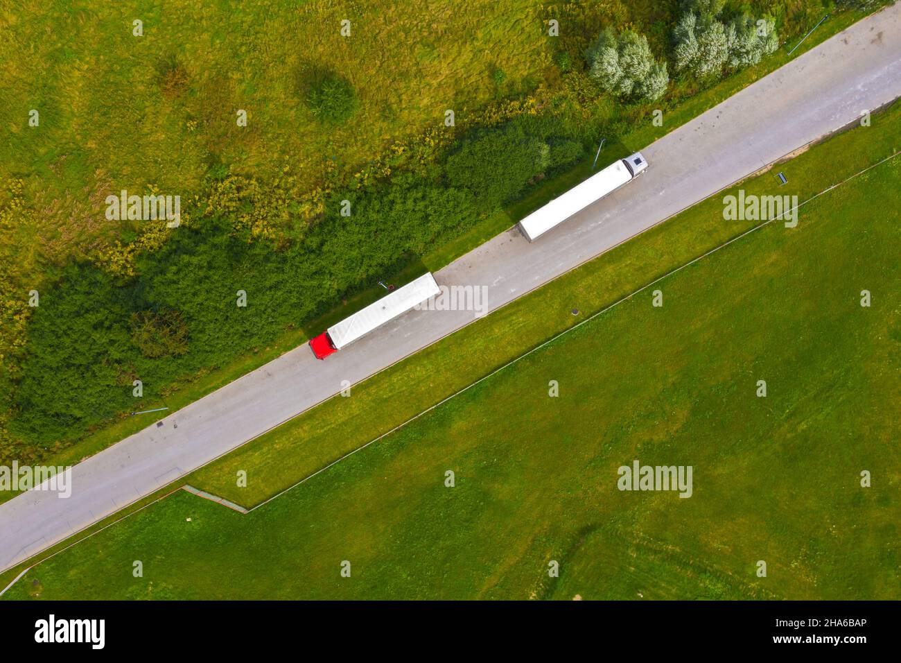 LKW-Logistik-Antenne. Zwei LKWs bewegen sich auf der Straße zwischen Feldern. Blick von der Drohne. Stockfoto