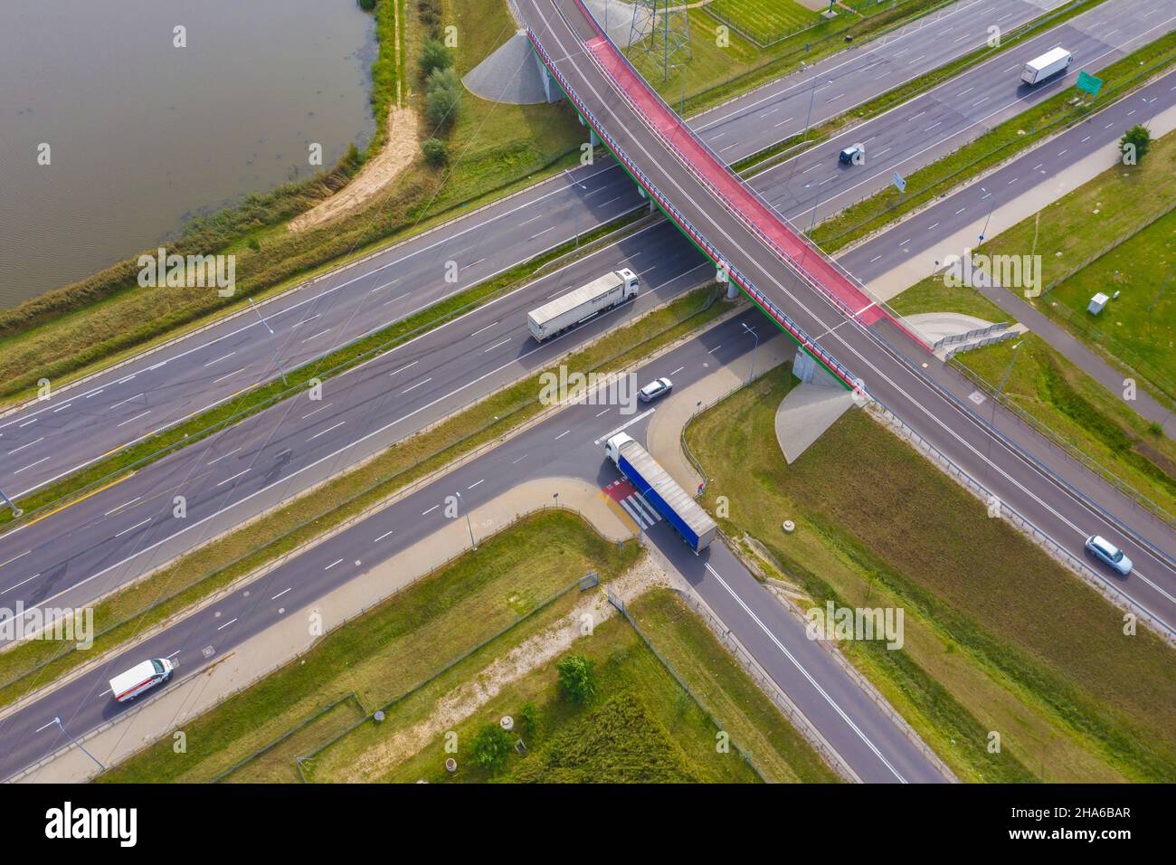 LKW-Logistik-Antenne. Lastwagen bewegen sich durch die Autobahn Kreuzung Straße zwischen Feldern. Blick von der Drohne. Stockfoto