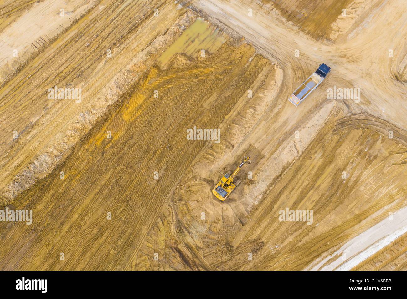 Luftbild des Baggers gießt Sand in den Wagen. Auf der Baustelle Ansicht von oben. Schießen von der Drohne. Stockfoto