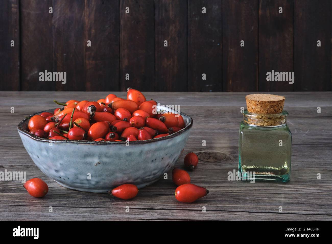 Hunderose (Rosa Canina), roter Hagebuttenöl-Extrakt und natürliche rote Früchte auf einer Schüssel Stockfoto
