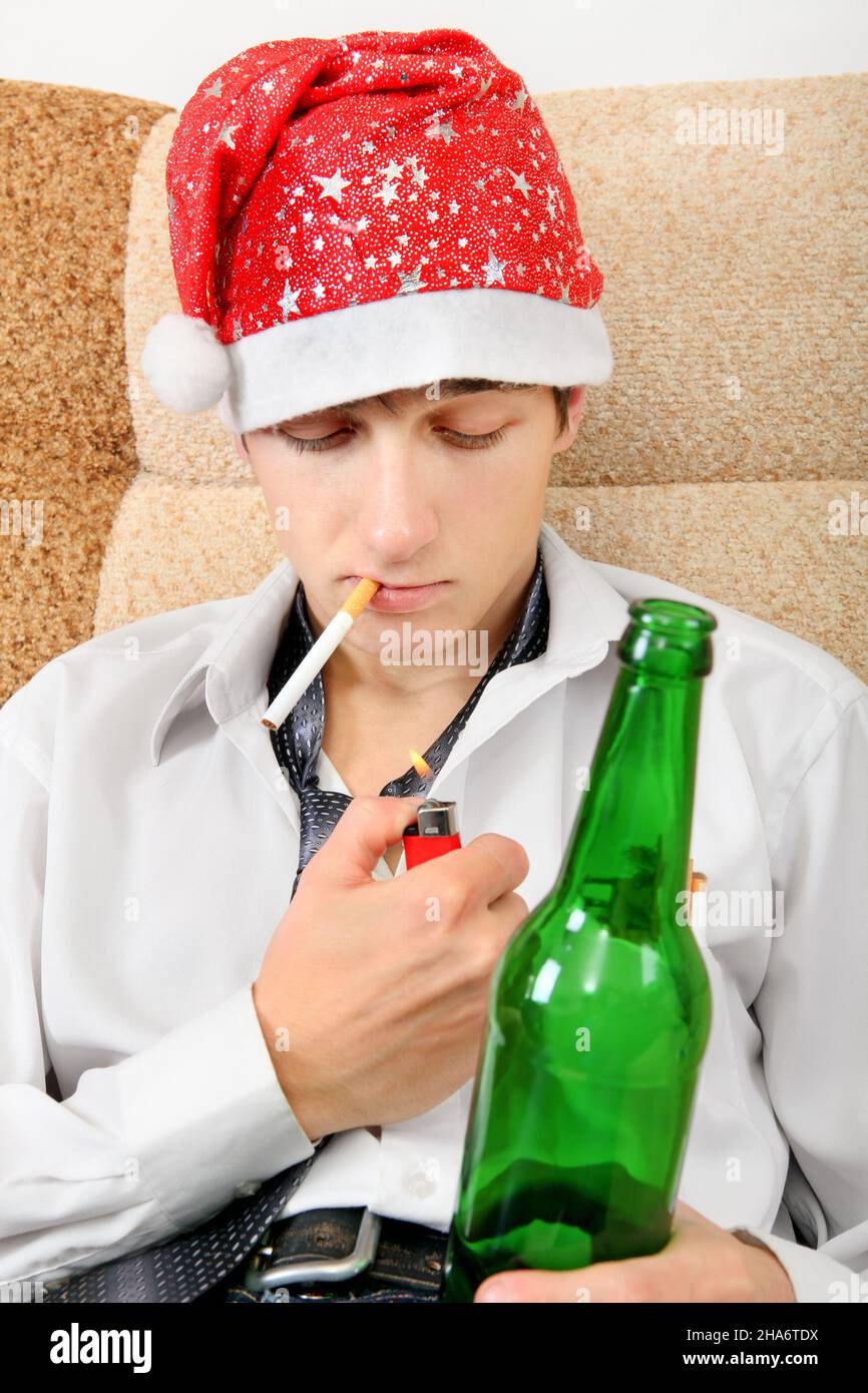 Teenager in Weihnachtsmütze mit einer Flasche Bier, die Zigarette raucht  Stockfotografie - Alamy