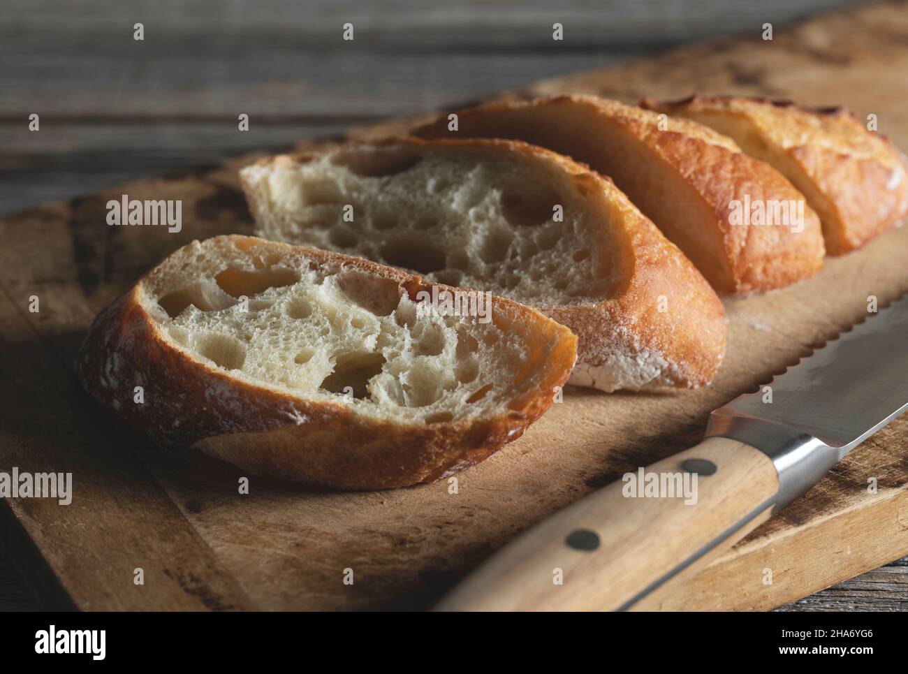 Ein geschnittenes Baguette auf einem alten Holzschneidebrett. Nahaufnahme. Stockfoto