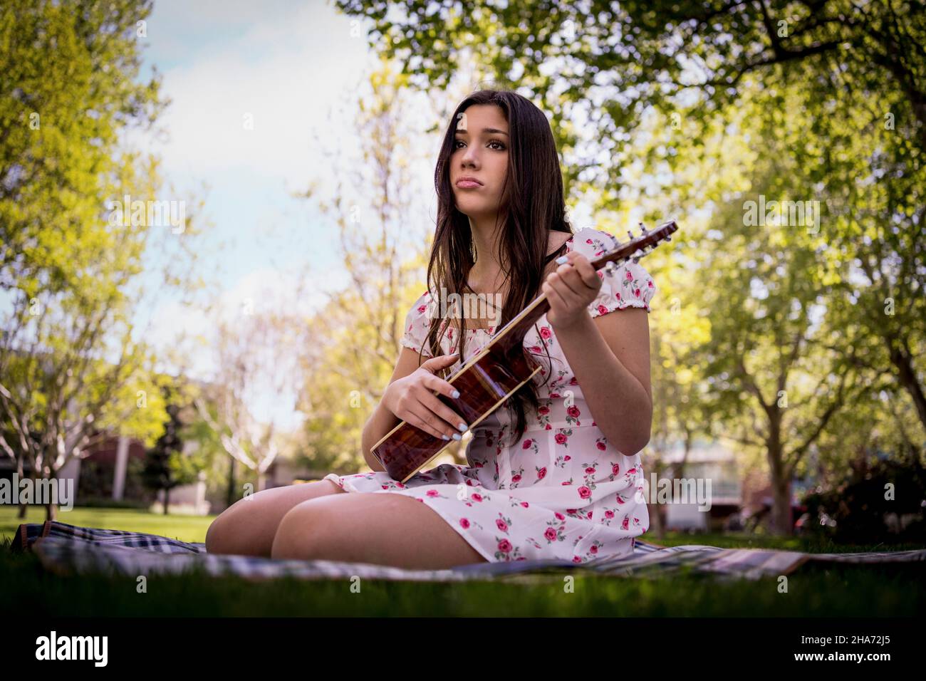Traurige Latina Teen Weiblich spielt Ukulele im Park Stockfoto