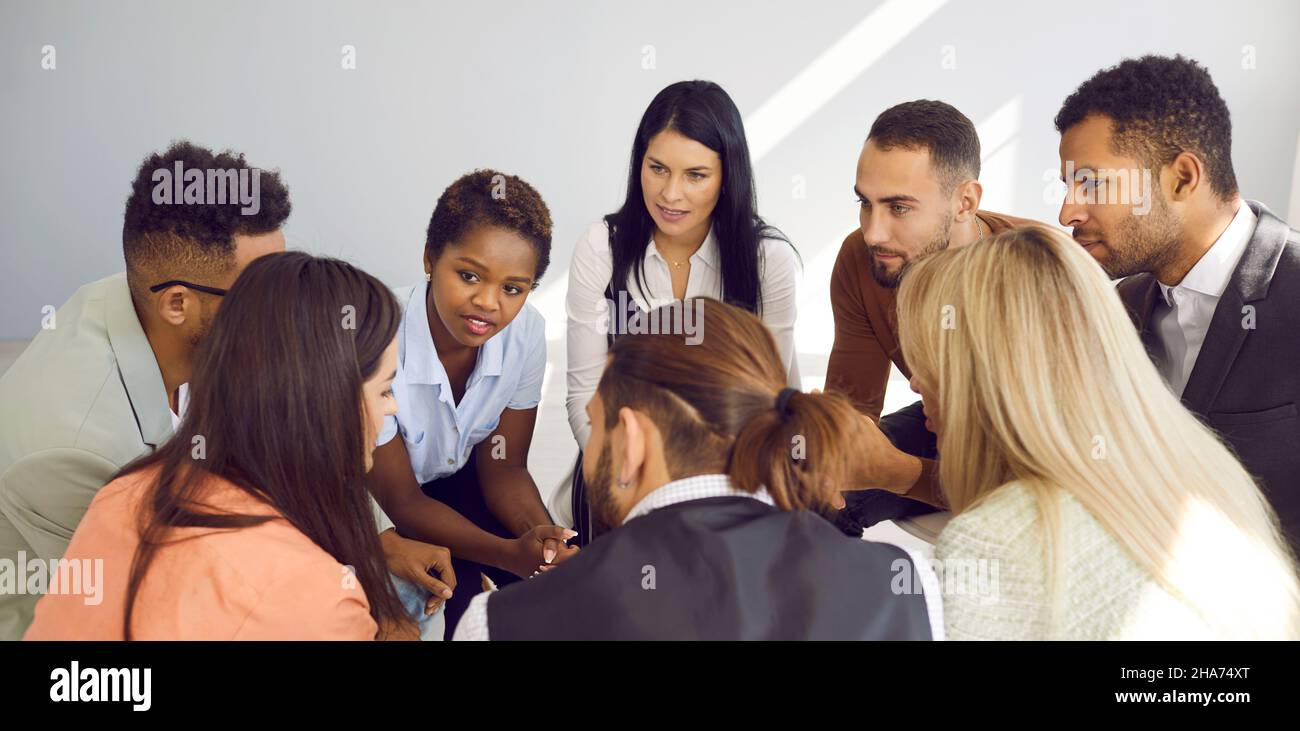 Gruppe von multirassischen Menschen, die ein Gespräch führen und einer jungen Frau zuhören Stockfoto