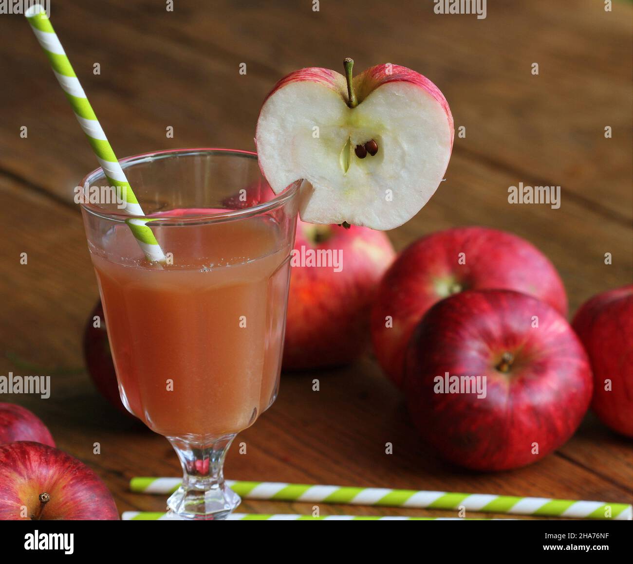 Frischer Apfelsaft im Glas mit rotem Apfel auf rustikalem Holztisch. Selektiver Fokus, Stockfoto