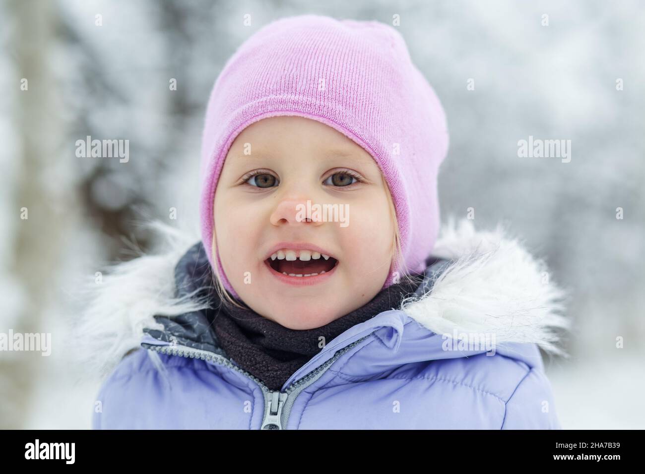 Winterkleidung. Jacke in warmem Lila und pinkfarbener Hut. Winterurlaub. Stockfoto