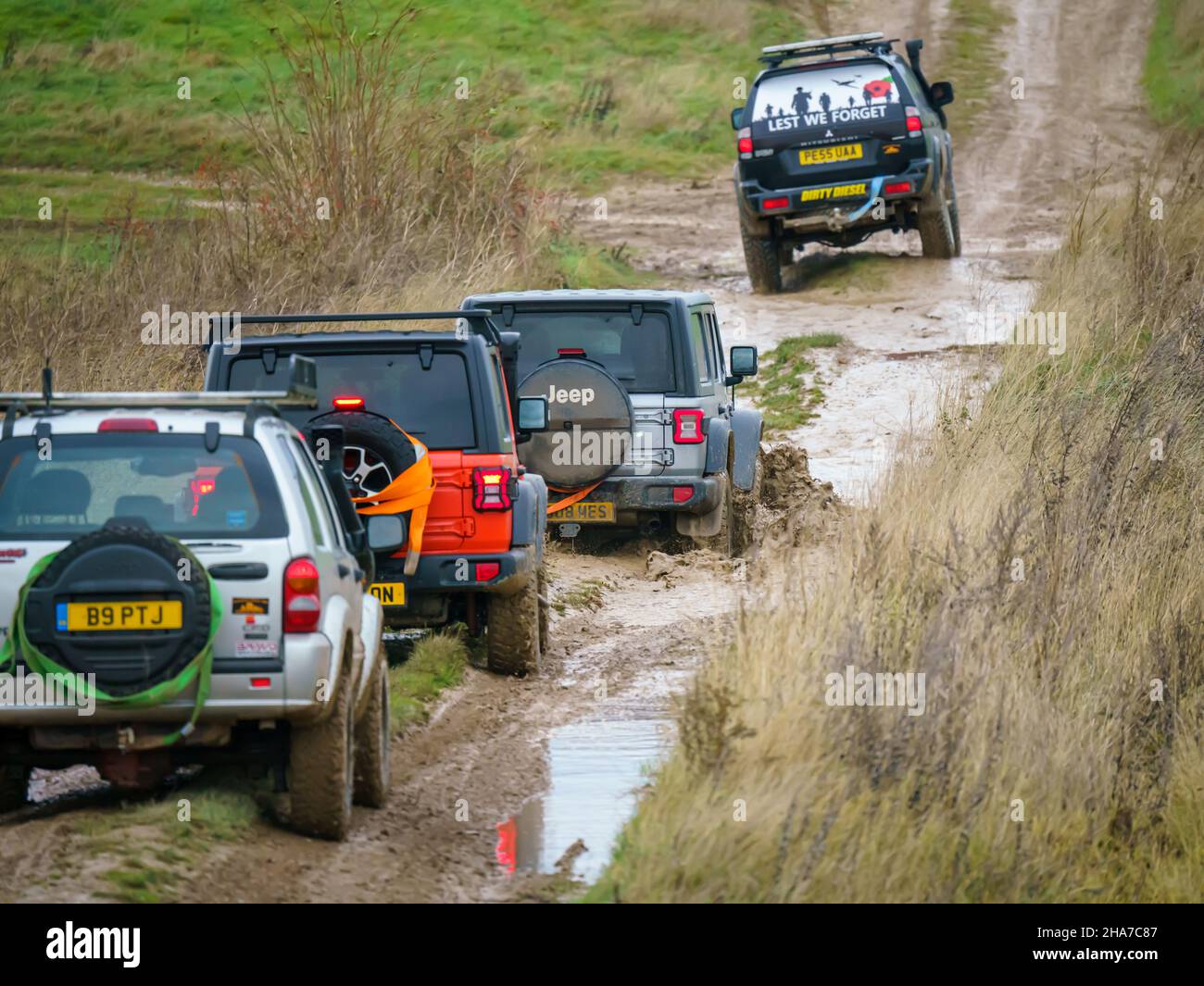 Geländewagen im Geländewagen, die über Schlamm und Wasser geloggte Gelände fahren, Salisbury Plain Wilts UK. Jeep Rubicon und Cherokee Stockfoto