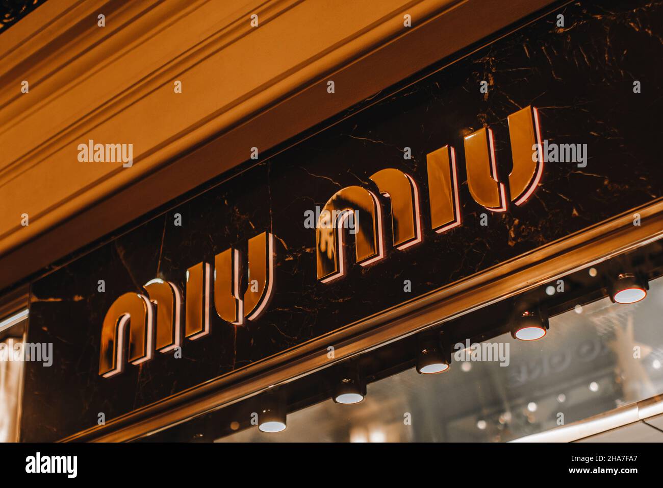 Goldenes leuchtendes Logo, Miu Miu Luxusgeschäft. Miu Miu ist eine italienische High-Fashion-Marke für Damenbekleidung und Accessoires. Stockfoto