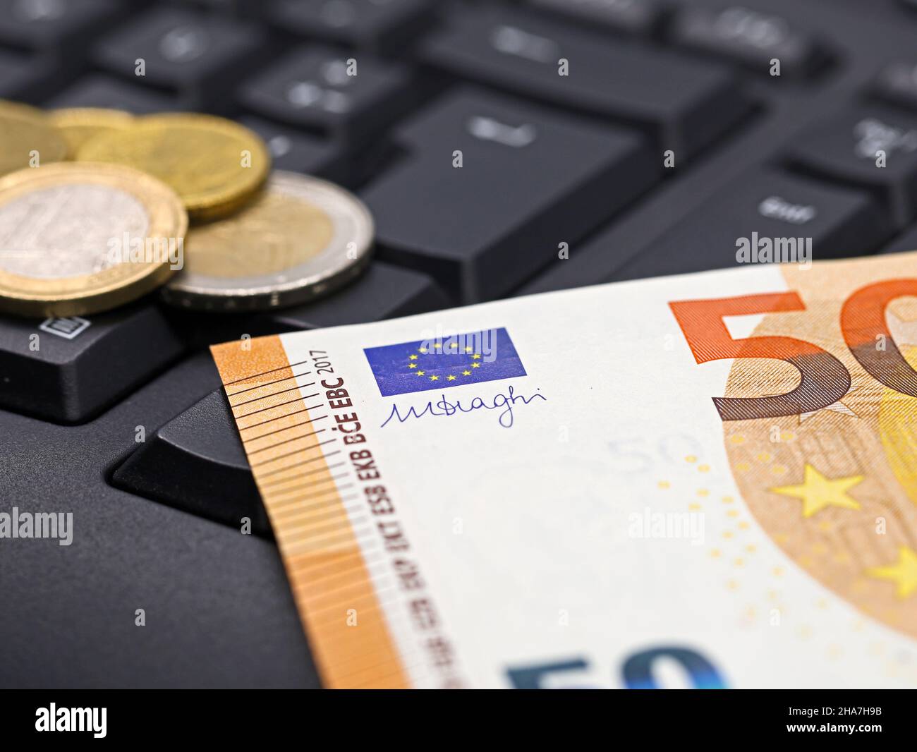 Euro-Geldschein und Münzen auf der Tastatur des Computers, Nahaufnahme, Konzeptbild des Online-Banking Stockfoto