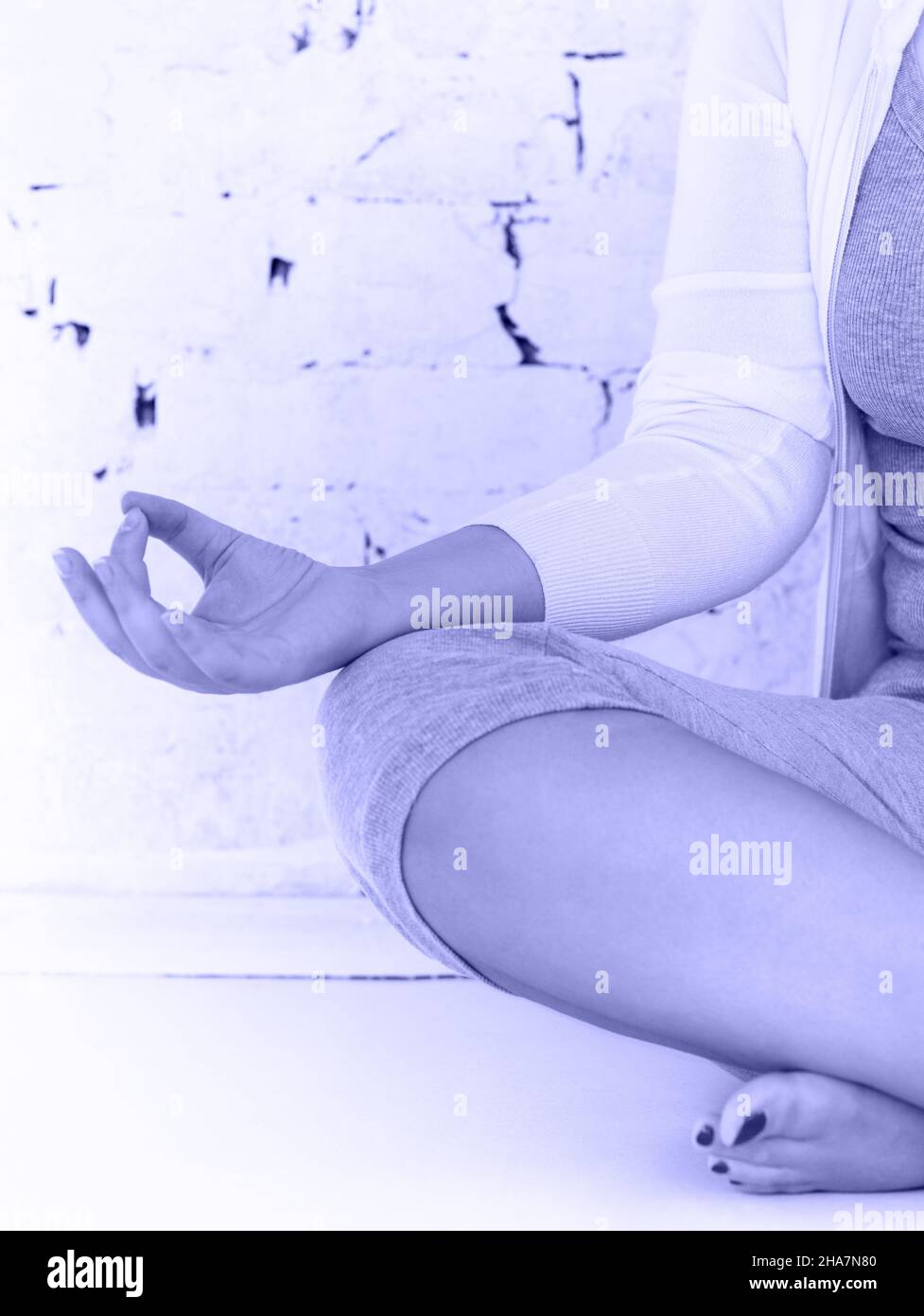 Attraktive junge Frau, die Yoga macht. Konzentrieren Sie sich auf die Hand. Farbe 2022 Jahre, sehr peri, violett Stockfoto