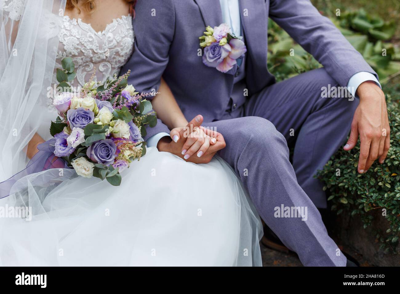 Das Paar umarmte sich auf ihrer Hochzeit. Trendige Farbe des Jahres 2022 in der Hochzeit. Braut hält Bouquet und umarmt Bräutigam in sehr Peri Anzug. Stockfoto