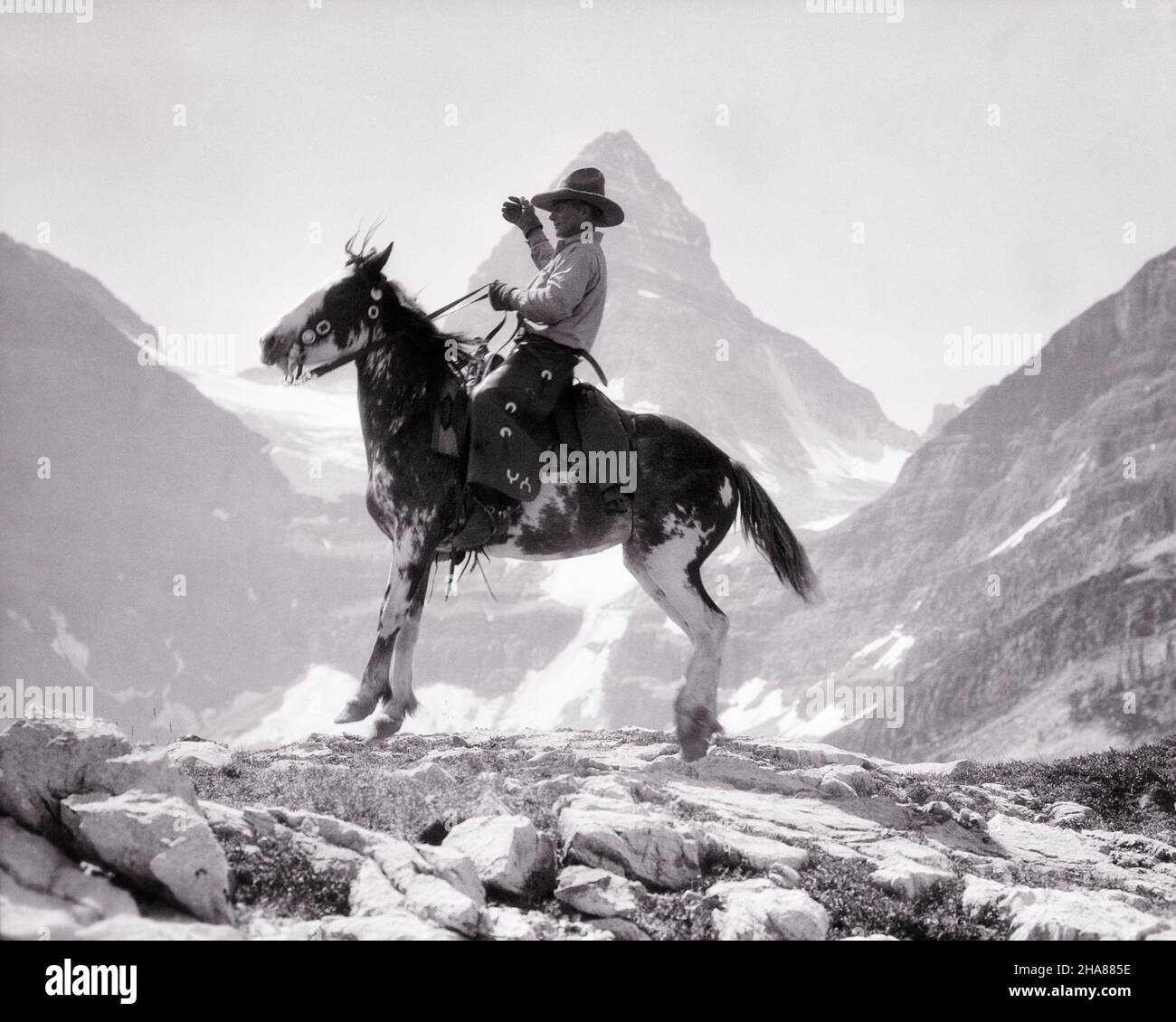 1920S COWBOY, DER AUF DEM PONY PINTO REITEND, REITEND, REITEND, AUF EINER BERGKETTE IN FELSIGEN BERGEN GEGEN MT ASSINIBOINE KANADA - H1830 HAR001 HARS MÄNNER RISKIEREN PONY WESTERN SPIRITUALITY CONFIDENCE B&W NORTH AMERICA SÄUGETIERE WELLNESS ABENTEUER STÄRKE MUT AUFREGUNG RECREATION RIDGE STOLZ AUF BERUFE ASSINIBOINE CONCEPTUAL MT STYLISH ELEVATION PINTO SOLITUDE ALBERTA SÄUGETIER MITTLEREN ERWACHSENEN MITTLEREN ERWACHSENEN MANN ENTSPANNUNG FELSIG BERGE SCHWARZ-WEISS BRITISH COLUMBIA KAUKASISCHE ETHNIE HAR001 ALTMODISCH Stockfoto