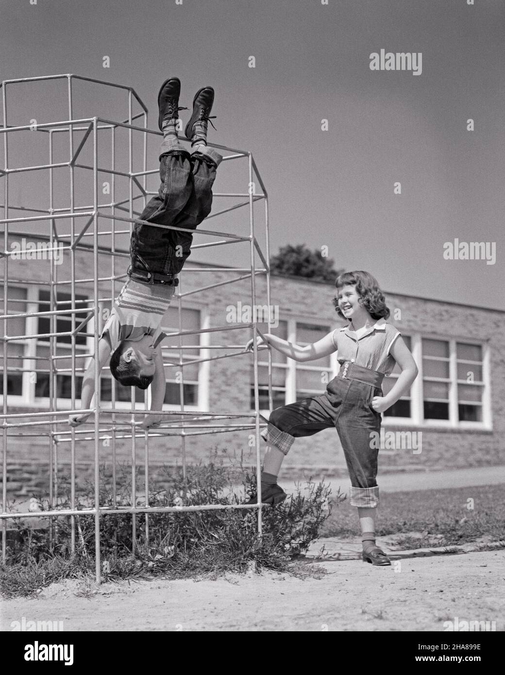 1950S JUNGE UND MÄDCHEN SPIELEN AUF SPIELPLATZ DSCHUNGEL FITNESS-STUDIO JUNGE ZEIGEN, HÄNGEN KOPFÜBER VON DER BARS MÄDCHEN STEHEN BY LACHING - J5068 HAR001 HARS OLD FASHION SISTER 1 JUVENILE FRIEND BALANCE SAFETY COMPETITION BAUMWOLLE FREUDE LIFESTYLE DSCHUNGEL WEIBCHEN BRÜDER ZEIGEN LÄNDLICHE GESUNDHEIT KOPIEREN RAUM FREUNDSCHAFT GANZKÖRPERLICHKEIT PERSONEN MÄNNER RISKIEREN AUFWÄRTSPOTENZIAL GESCHWISTER VERTRAUEN DENIM SCHWESTERN B&W BARS SUMMERTIME HAPPINESS WELLNESS ABENTEUER FREIZEIT STRATEGIE UND AUFREGUNG ERHOLUNG STOLZ DURCH DIE MÖGLICHKEIT DER GESCHWISTER KONZEPTIONELL FREUNDLICH STILVOLLE BLAUE JEANS WACHSTUM INFORMELLE JUGENDLICHE PRE-TEEN Stockfoto