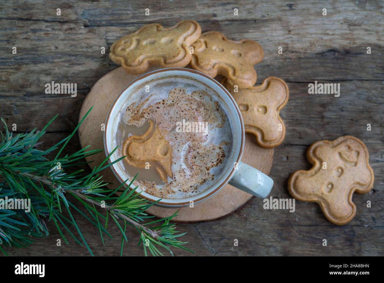 noel-Kekse, Cappuccino oder Latte-Kaffee und Lebkuchenkekse auf einem Holztisch, der mit Kiefernzweigen zu Weihnachten oder Neujahr geschmückt ist. Mann Stockfoto