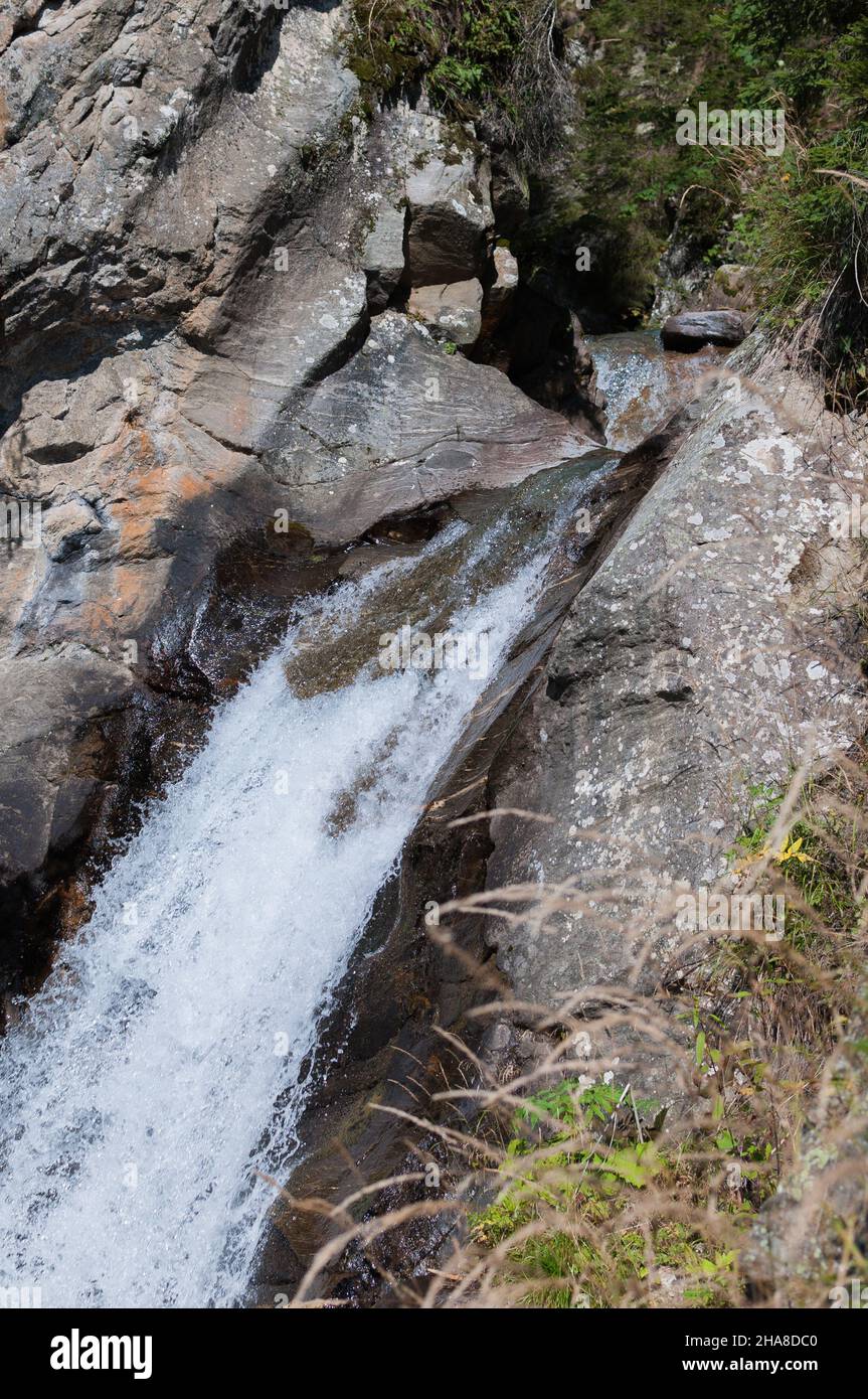 Kleiner Wasserfall in Berg- und Waldlandschaft an einem sonnigen Herbsttag Stockfoto