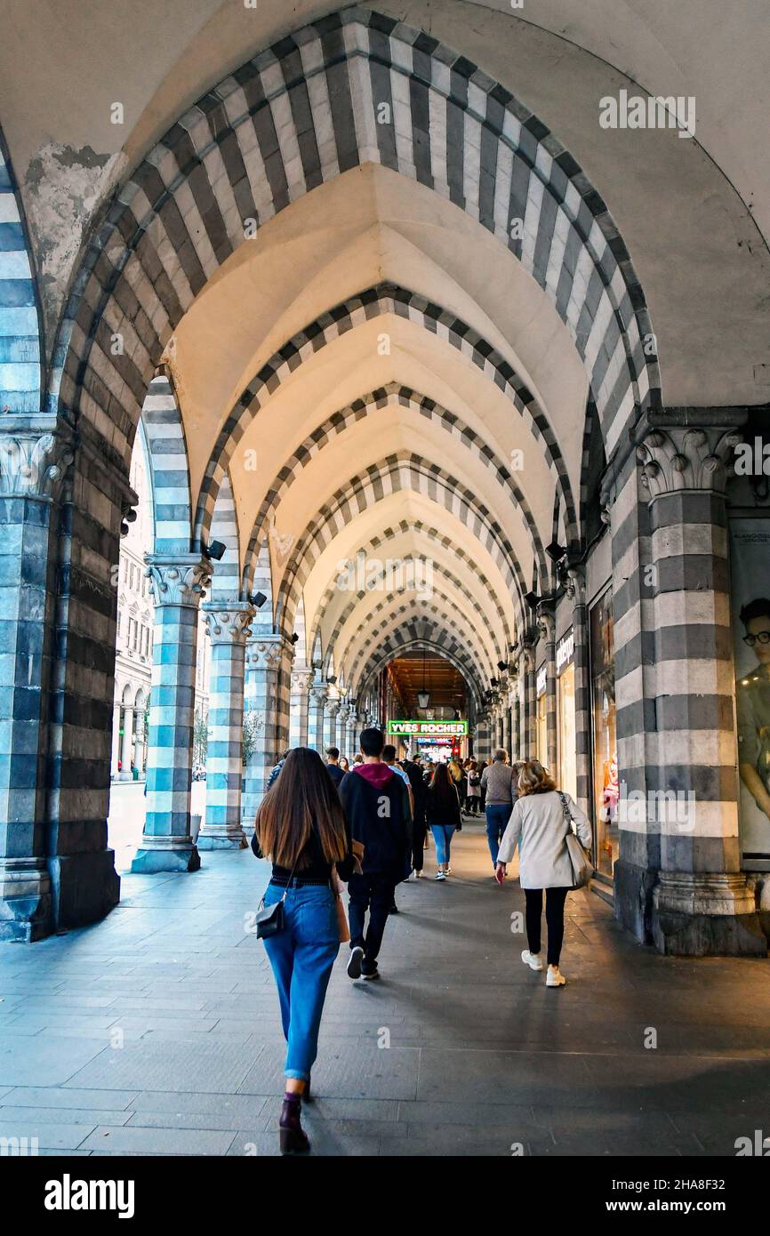 Menschen, die unter der Arkade im gotischen Stil der Via XX Settembre, einer der Hauptstraßen von Genua, Ligurien, Italien Stockfoto