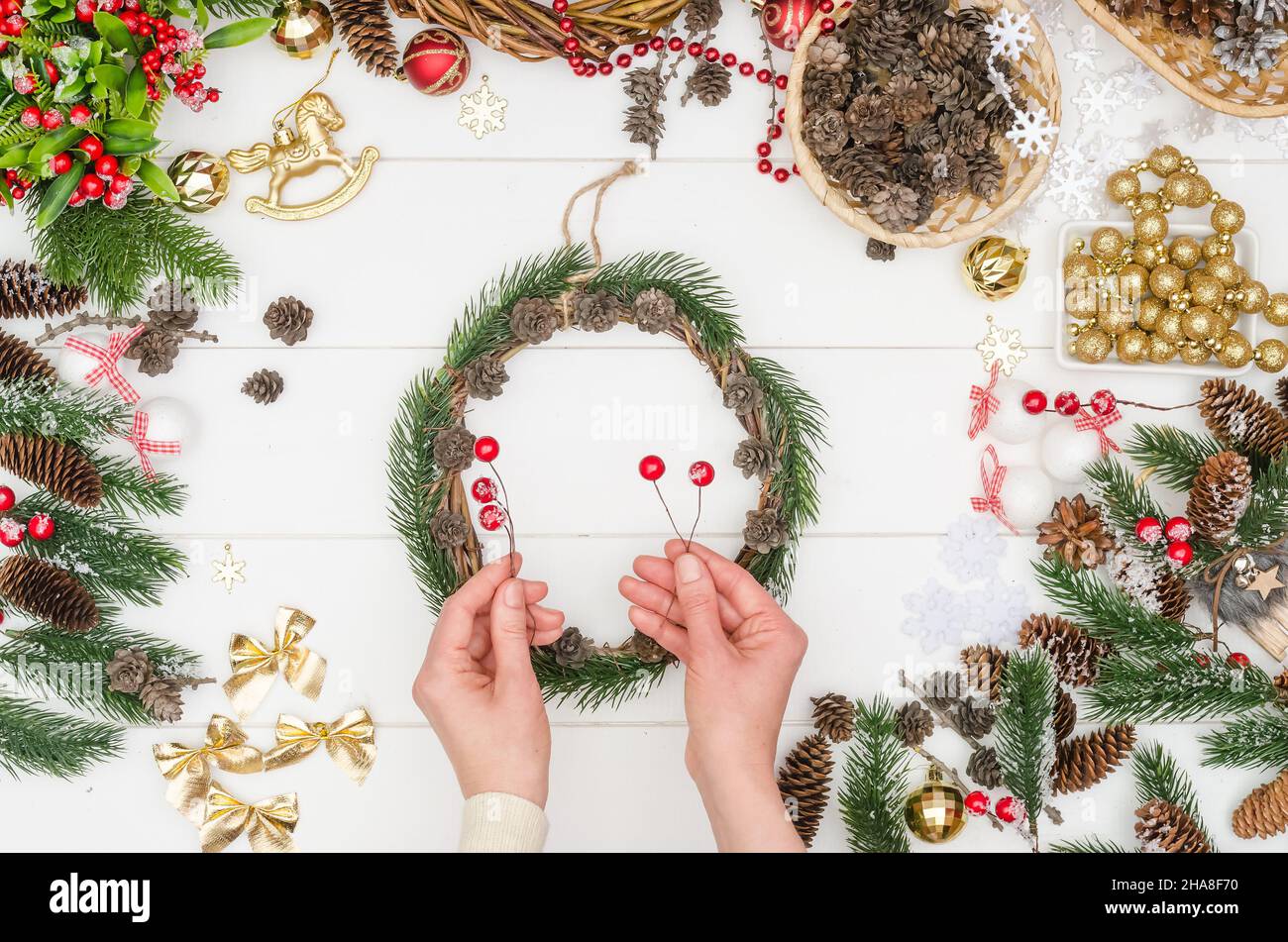 Schritt für Schritt einen kleinen Weihnachtskranz machen, Schritt 5 - künstliche rote Beeren auf einen Draht nehmen Stockfoto