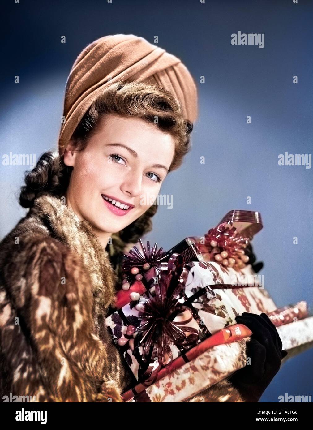 1940S FRAU IM KUNSTPELZMANTEL, DIE DIE KAMERA MIT EINEM STAPEL FESTLICH GEWICKELTER WEIHNACHTSGESCHENKE BETRACHTET - X509C HAR001 HARS STIL EVE JUNGE ERWACHSENE FRIEDEN FREUDE LIFESTYLE FEIER FRAUEN PORTRÄTS ERWACHSENE DAMEN PERSONEN ERWACHSENE PAKET AUSDRÜCKE WINTERZEIT WINTERSAISON KOPF UND SCHULTERN FRÖHLICH FROHE FEIERTAGE JAHRESZEITEN LÄCHELT DEZEMBER FEIERTAG WEIHNACHTEN UPDO DEZEMBER 25 SIEG ROLLT FRÖHLICHE PELZPELZE STILVOLL TURBAN FREUDIGE PAKETE SAISON JUNGE ERWACHSENE FRAU KAUKASISCHE ETHNIE HEILIGABEND FRISUR HAR001 ALTMODISCH Stockfoto