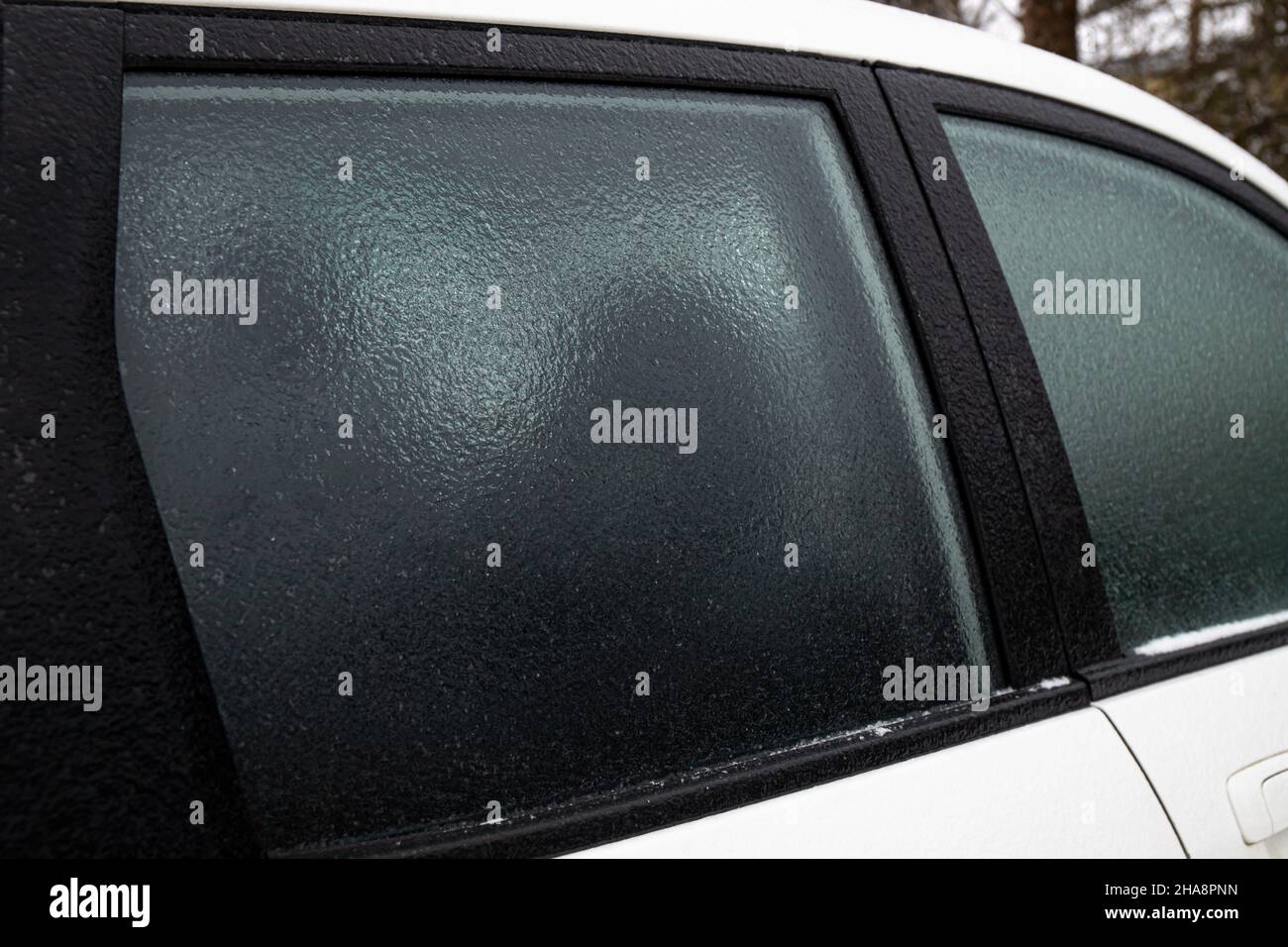 An kalten Wintertagen im Freien bedeckt die Glasscheibe des Autos eine Schicht Eisregen. Konzept für extreme Wetterbedingungen. Stockfoto